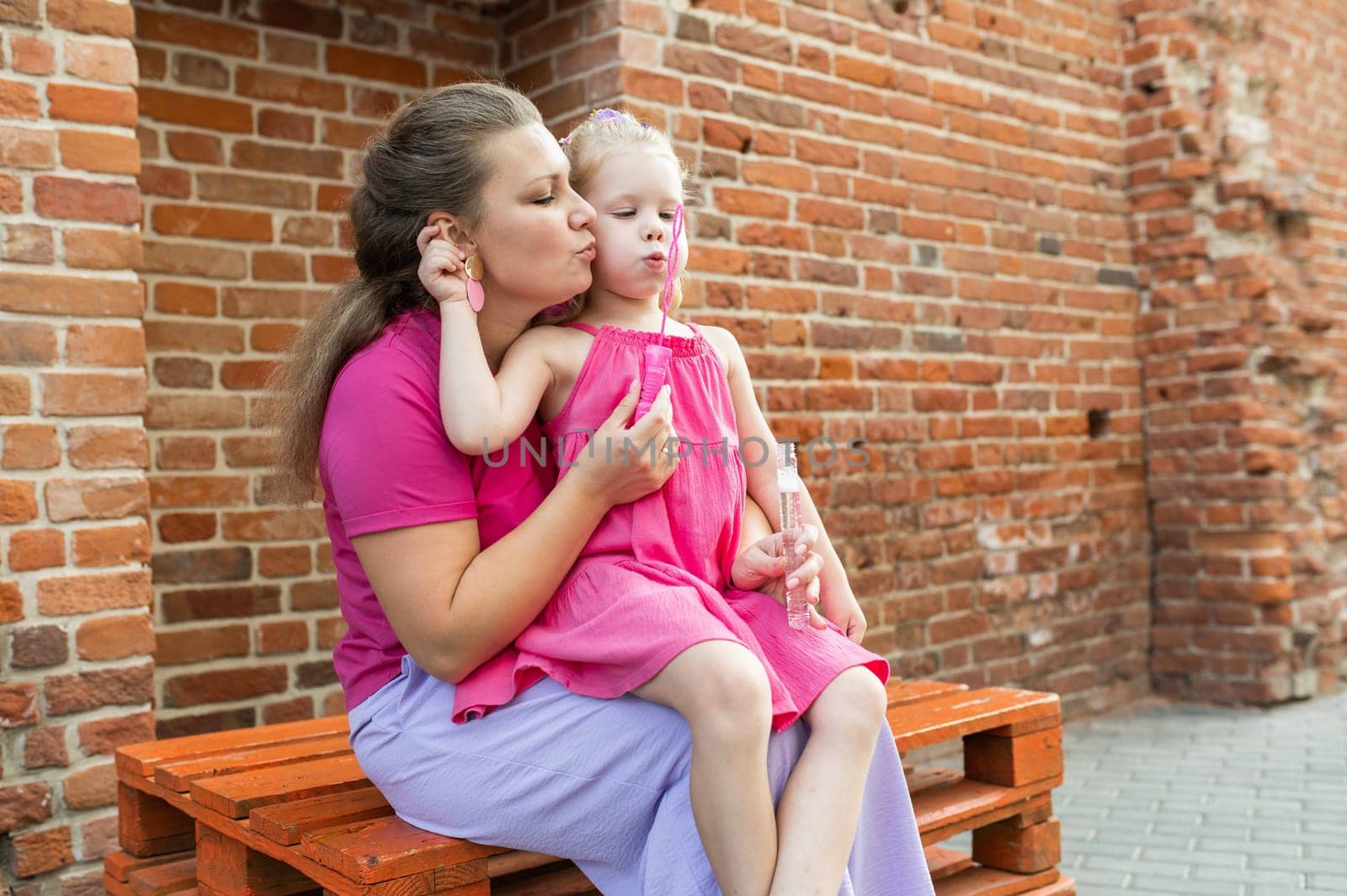 Deaf child with cochlear implant for hearing audio and aid for impairment having fun and laughs with mother outdoor in summer. Sound fitting device to help with communication listening and interaction.