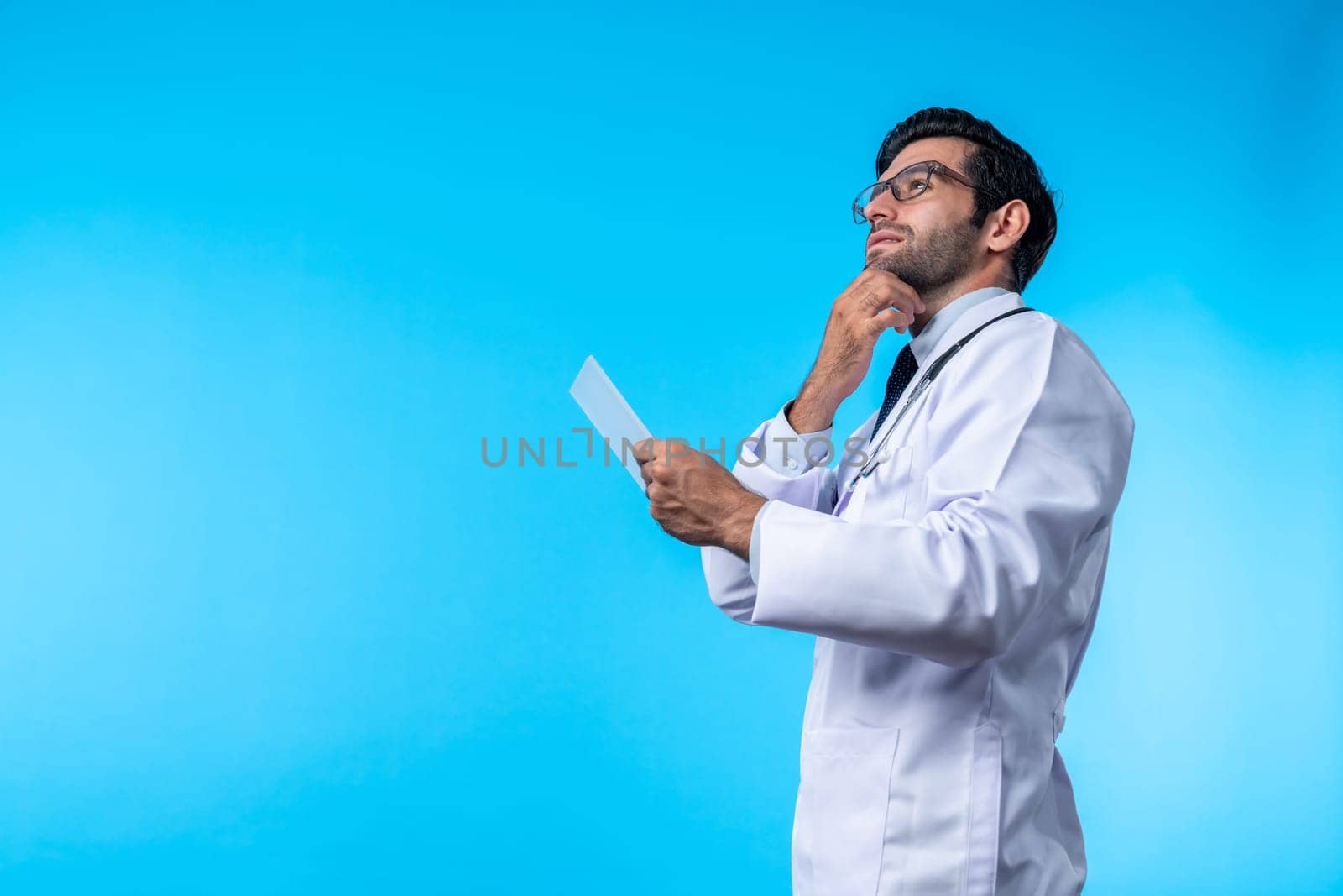 Caucasian smart doctor looking application form while thinking about medical theory. Professional doctor wearing glasses and lab coat while holding clipboard and standing with confident. Deviation.