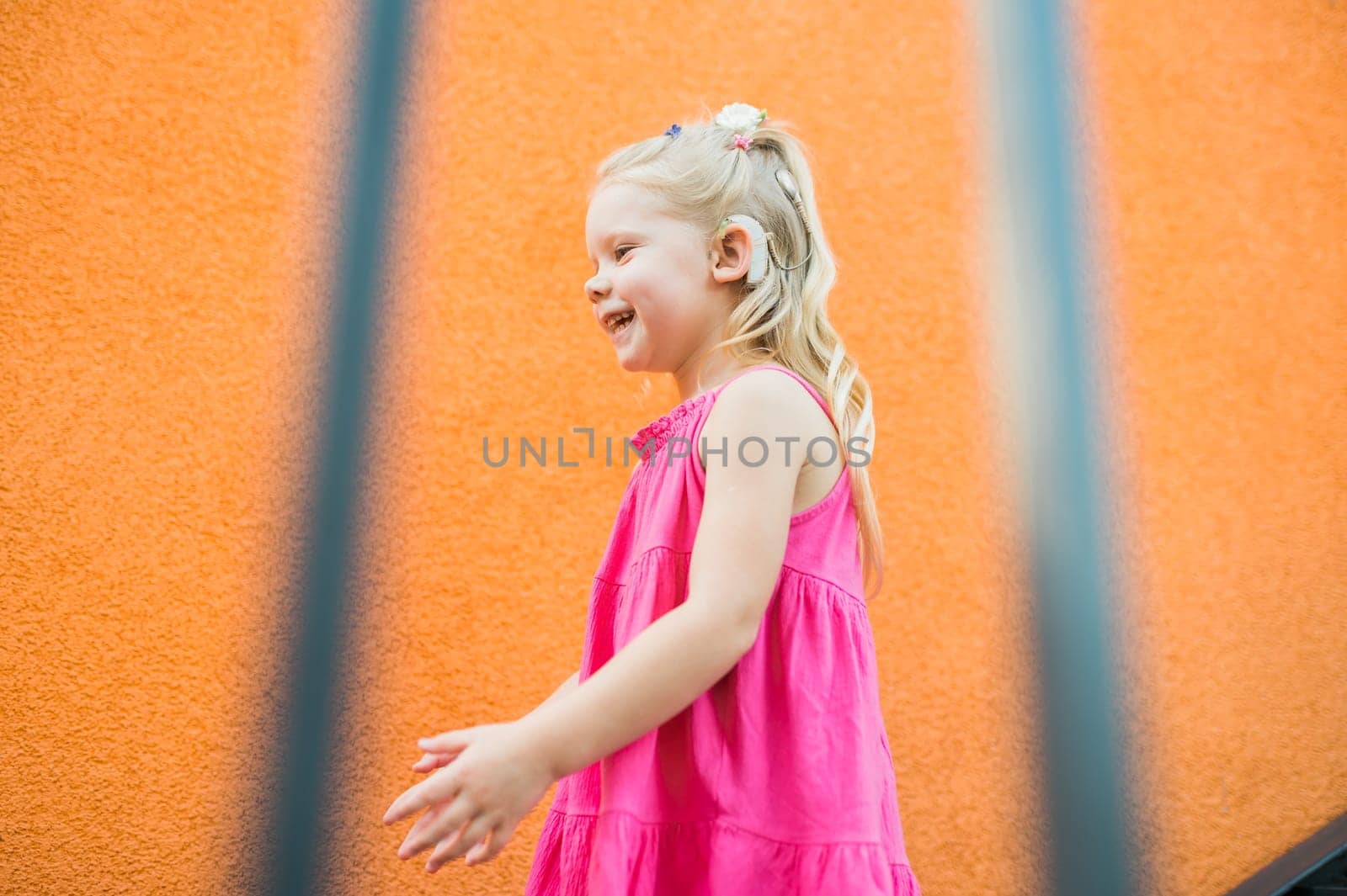 Child with hearing problem and cochlear implant dance in street, deaf kid began to hear. Hearing loss in childhood and treatment concept. Copy space and empty place for text.