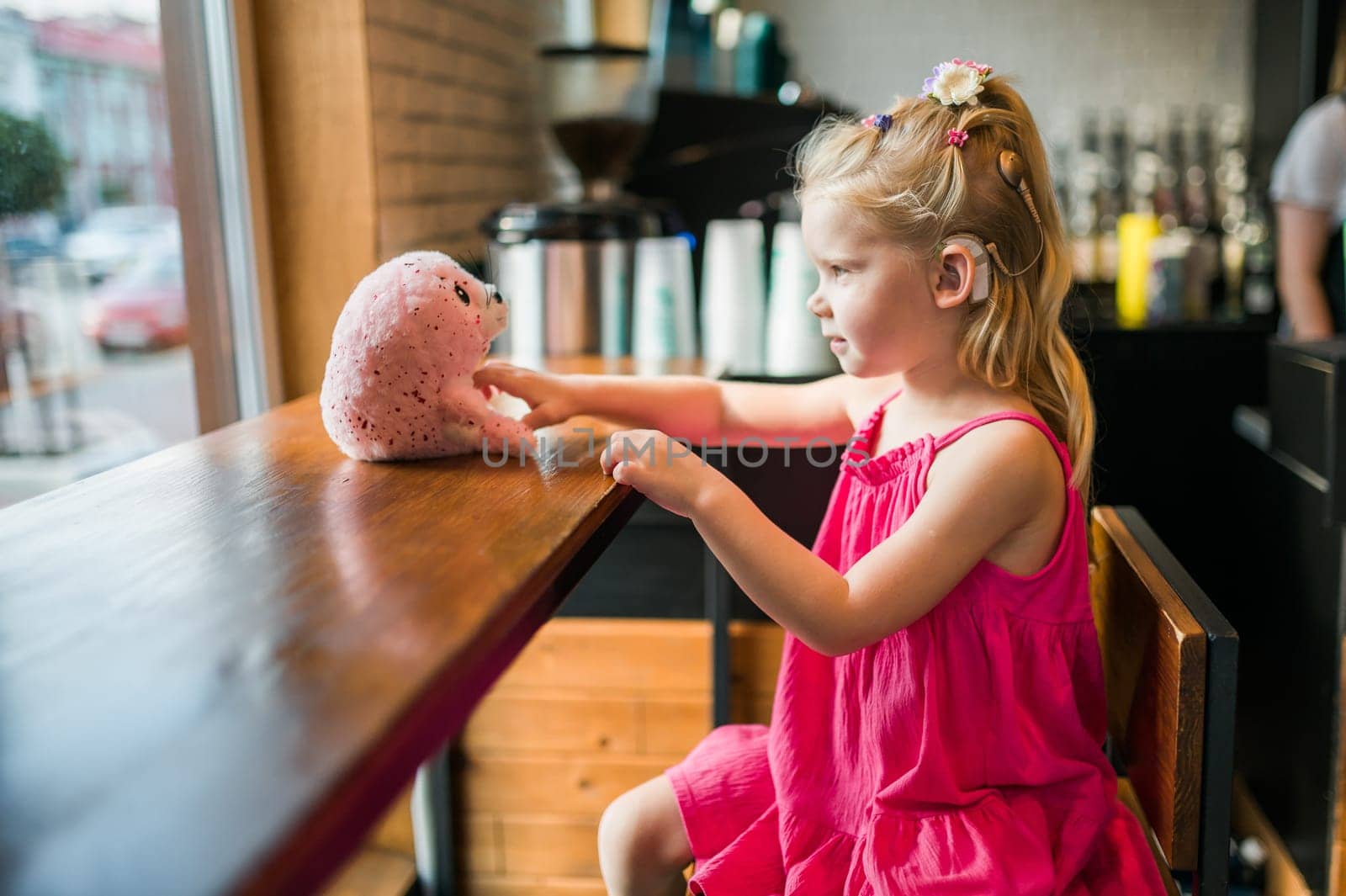 Child girl walks and have fun outdoor with cochlear implant on the head. Hearing aid and treatment concept. Copy space vertical.