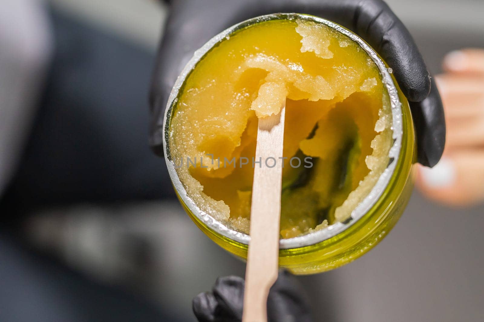 Orange body scrub with sugar and oil in glass jar in female hand. Homemade cosmetic for peeling and spa care. Copy space and empty place for advertising.