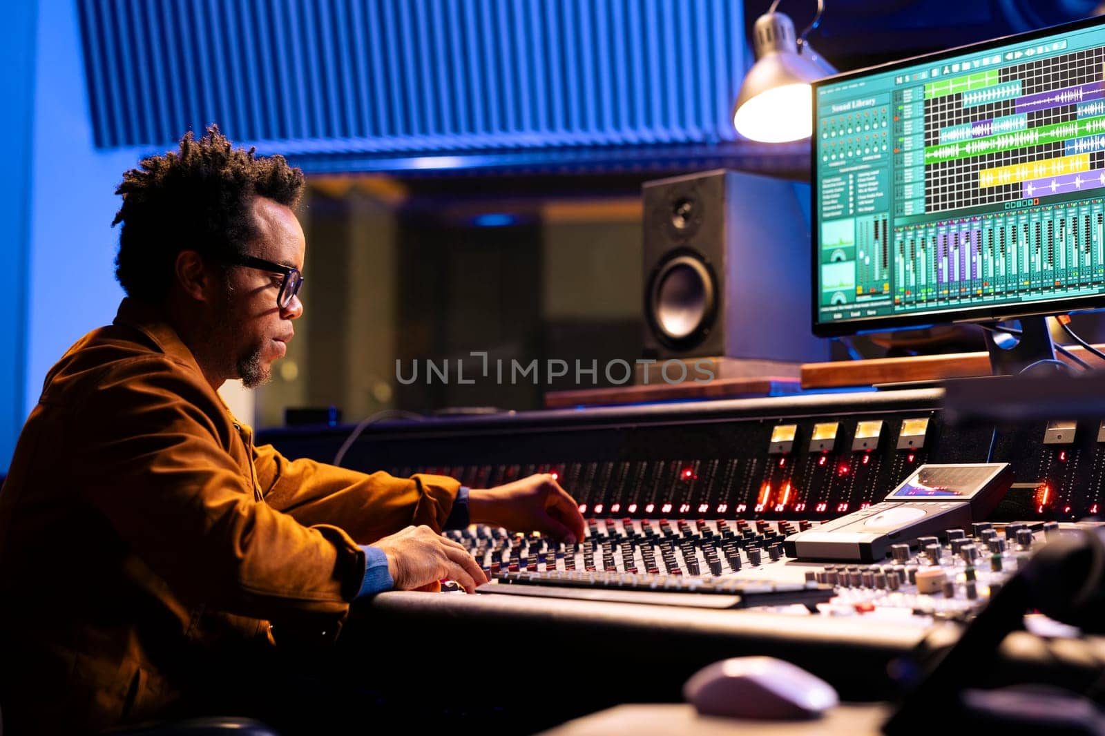 African american sound engineer works on mixing console with sliders and knobs by DCStudio