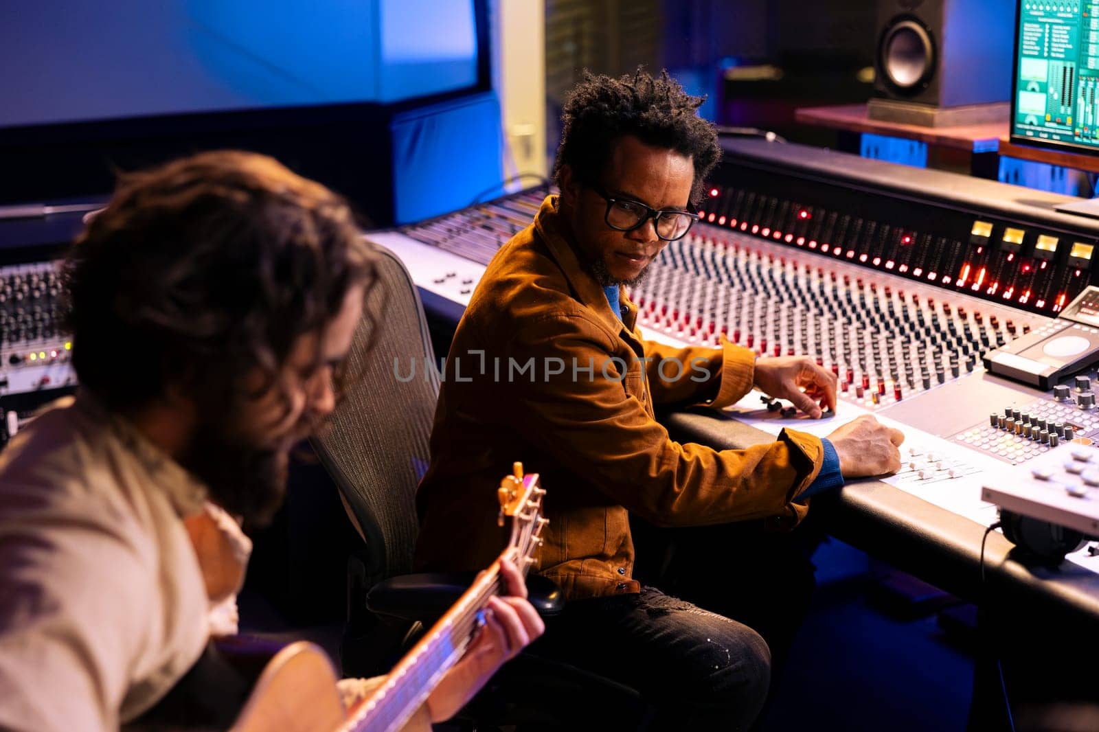Artist playing a new record on his guitar in control room by DCStudio