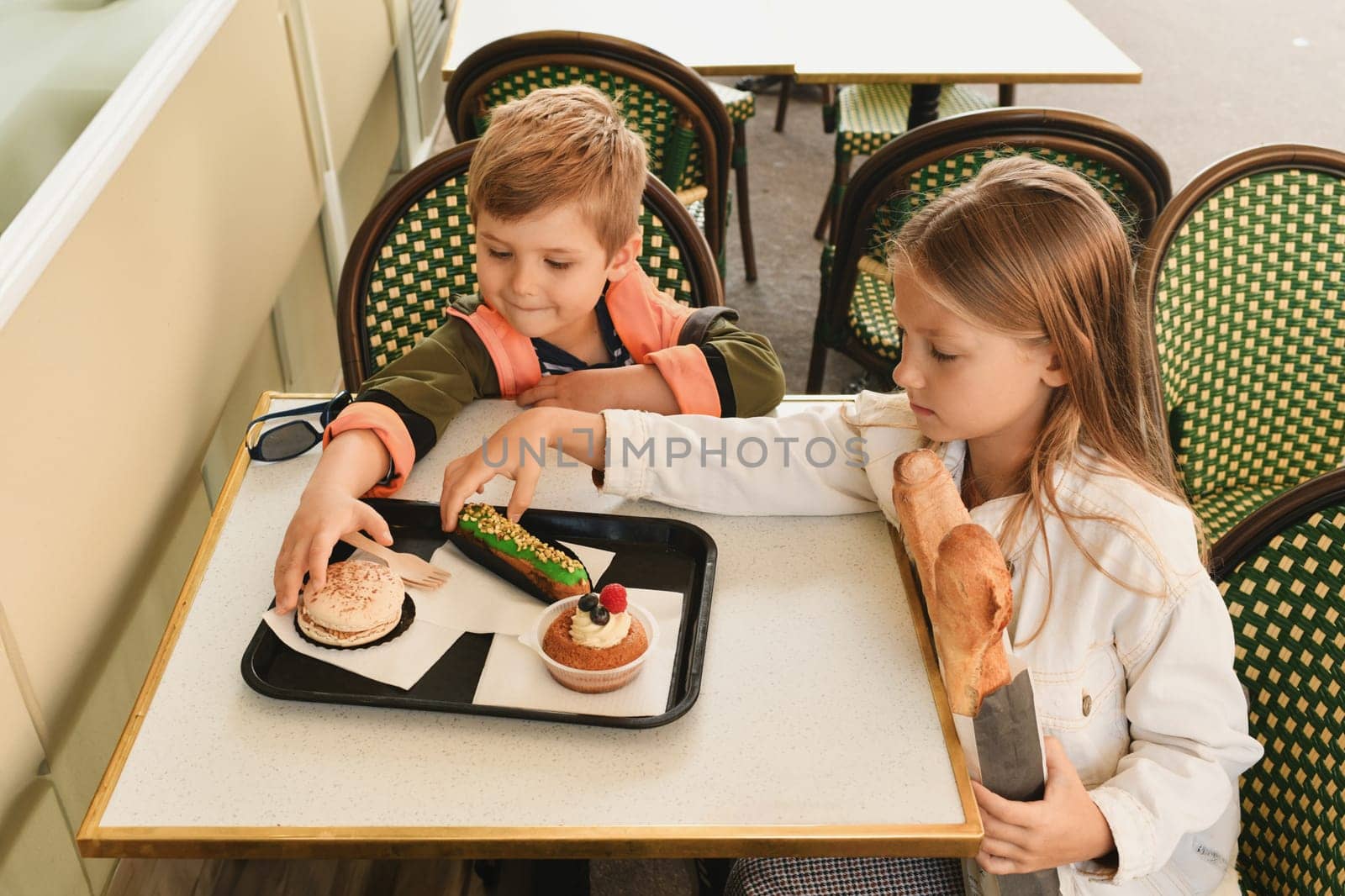 Brother and sister eat cakes in a French cafe Bakery