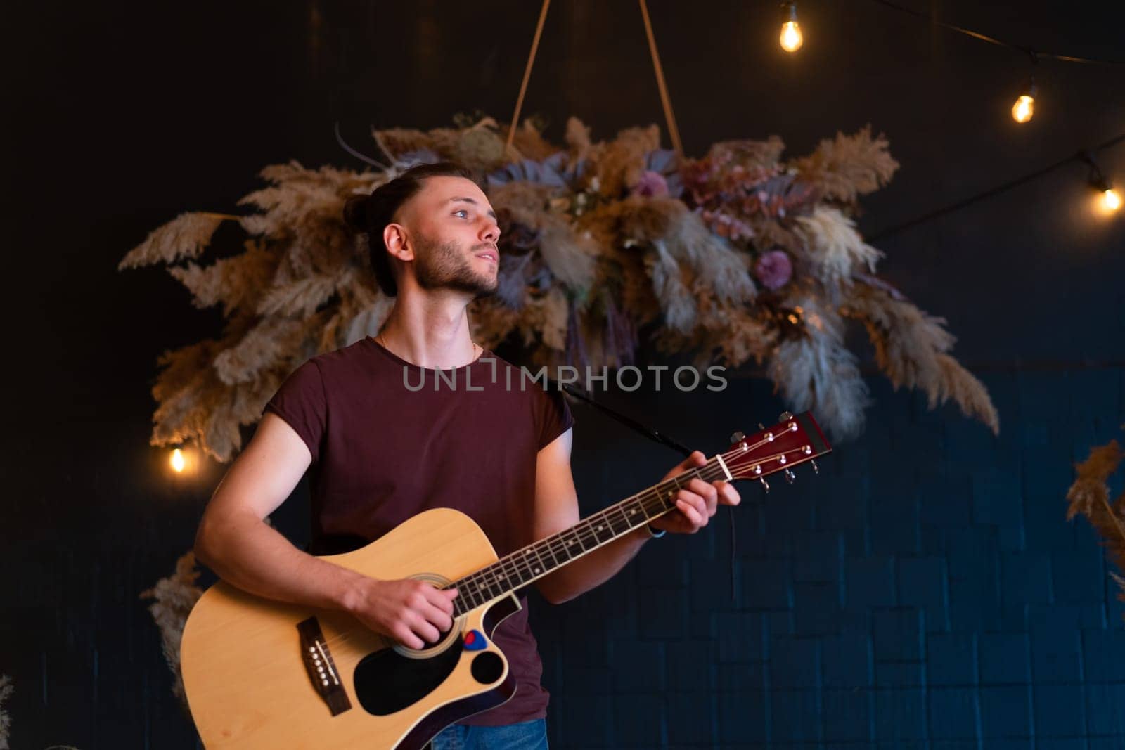 Male musician playing acoustic guitar. Guitarist plays classical guitar on stage in concert by andreonegin