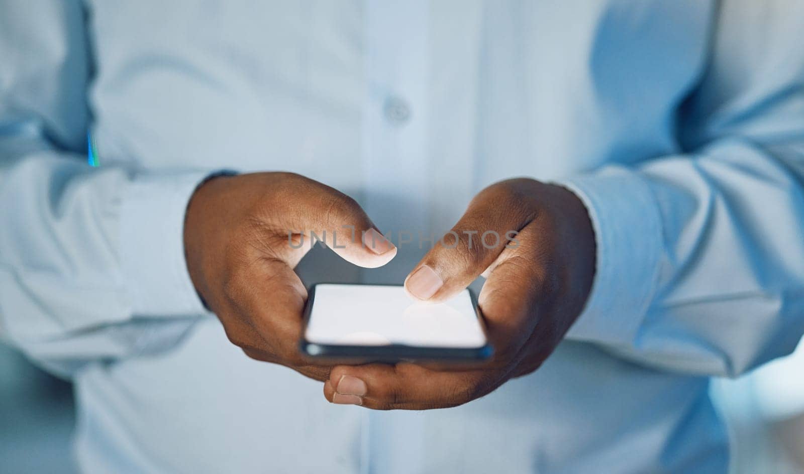 Man, hands and typing with phone for social media, online browsing or news at office. Closeup of African, male person or employee on mobile smartphone for chatting, texting or scrolling on app by YuriArcurs