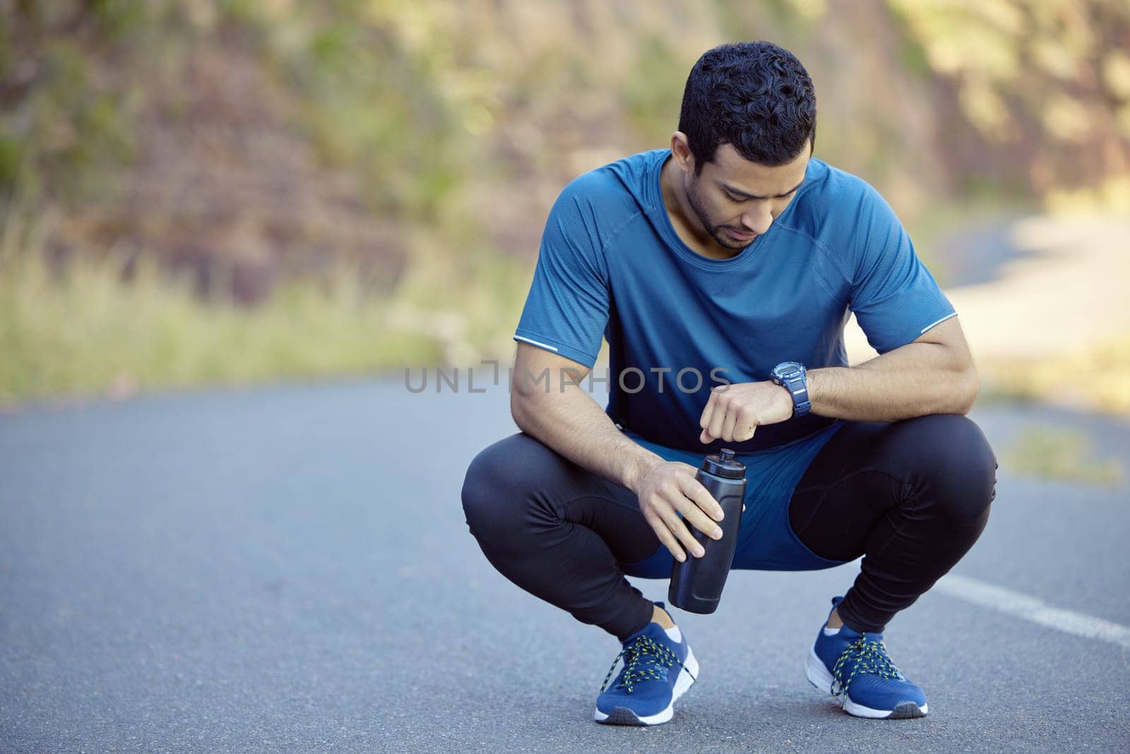Man, watch and tired athlete on break tracking training on mountain path for exercise, goals or check. Male person, street and resting with heart rate pulse for marathon running, workout or healthy.