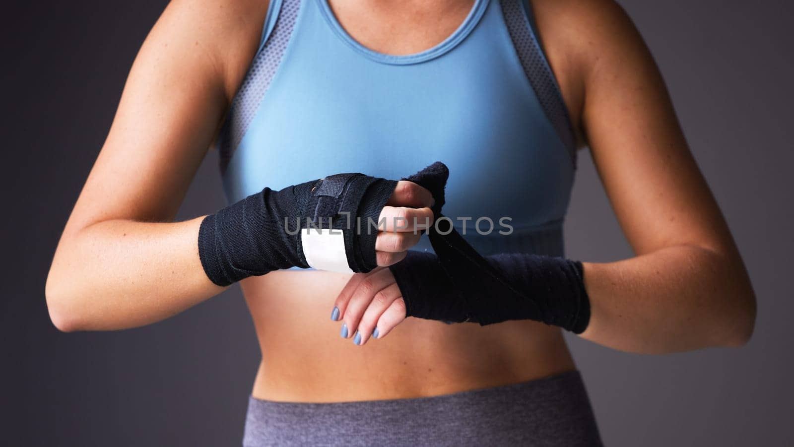Boxer, hand and wrapping for fitness, workout and warmup isolated on grey studio background. Woman, exercise and training for health, wellness and body performance for muscle power and cardio.