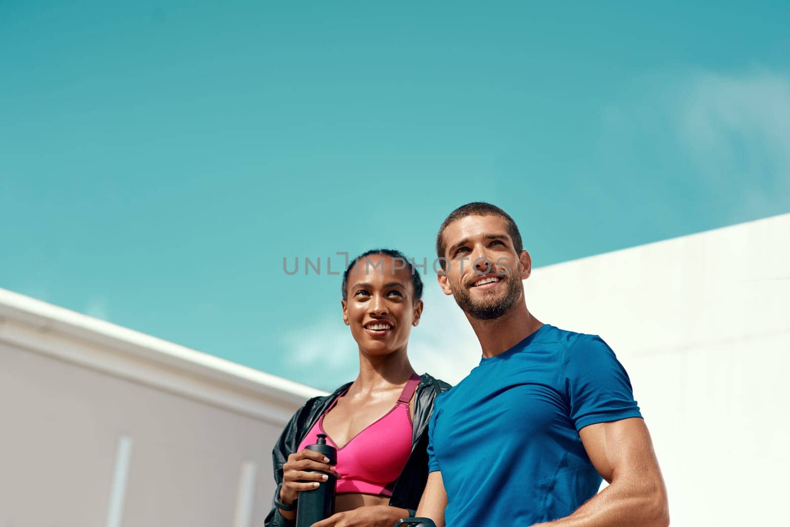 People, fitness and outdoor in sportswear for exercise, training or workout with blue sky. Personal trainer, man and woman together ready for thinking, gym and physical activity for summer body.
