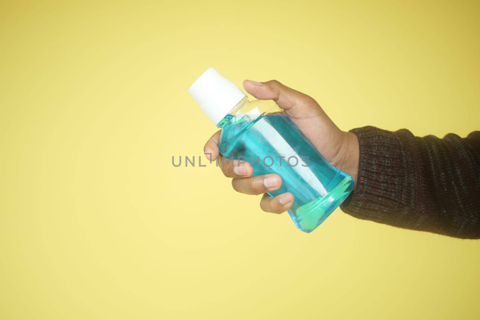 hand hold a mouthwash liquid container by towfiq007