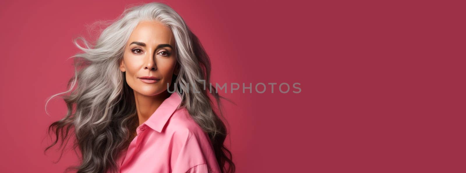 Elegant, elderly, chic Latino, Spain woman with gray long hair and perfect skin, pink background, banner. Advertising of cosmetic products, spa treatments, shampoos and hair care products, dentistry and medicine, perfumes and cosmetology for women