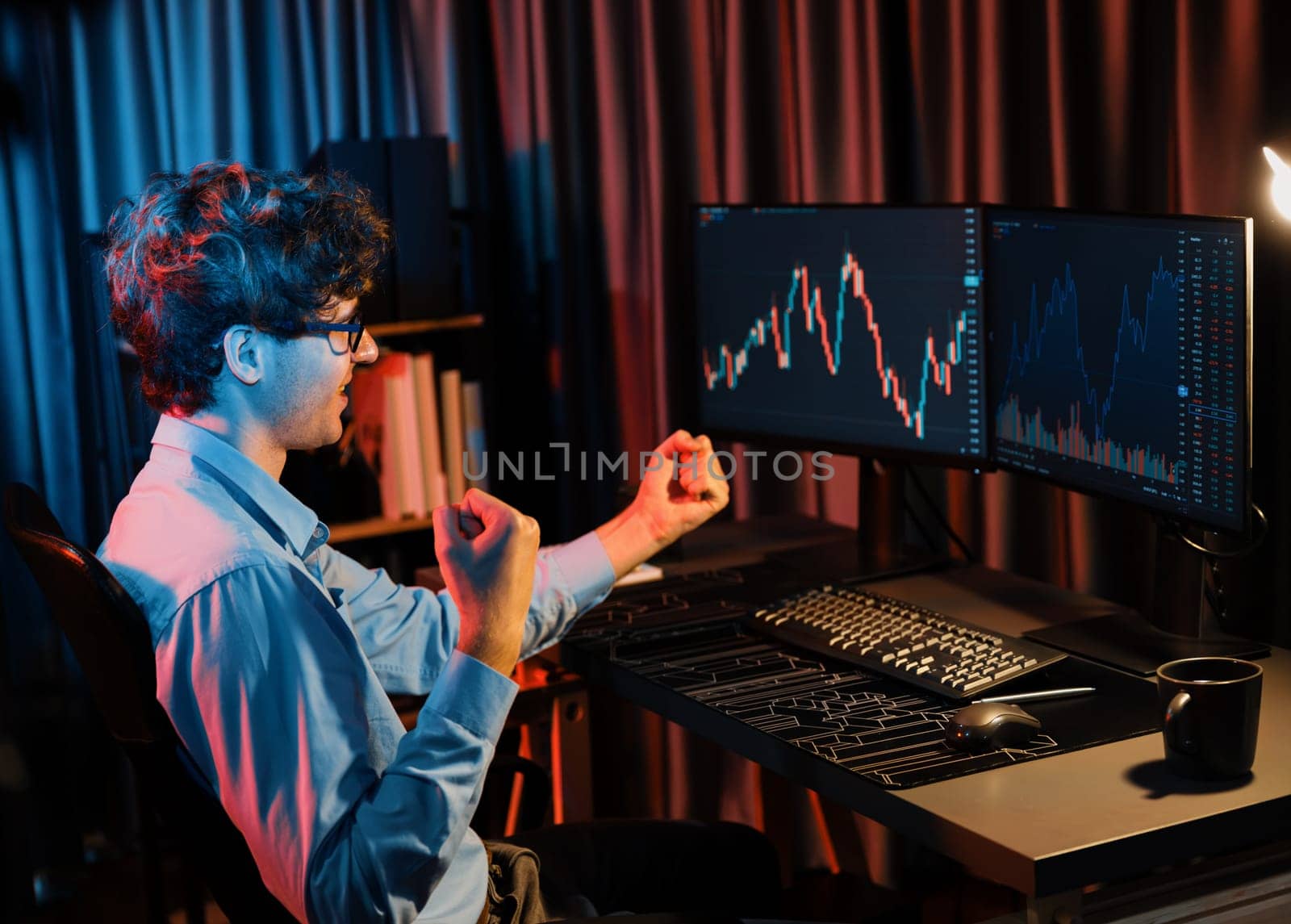 Successful business trader raising fist up with highest profit looking on global market online in real time at neon light modern office. Concept of dynamic stock exchange young businessman. Gusher.