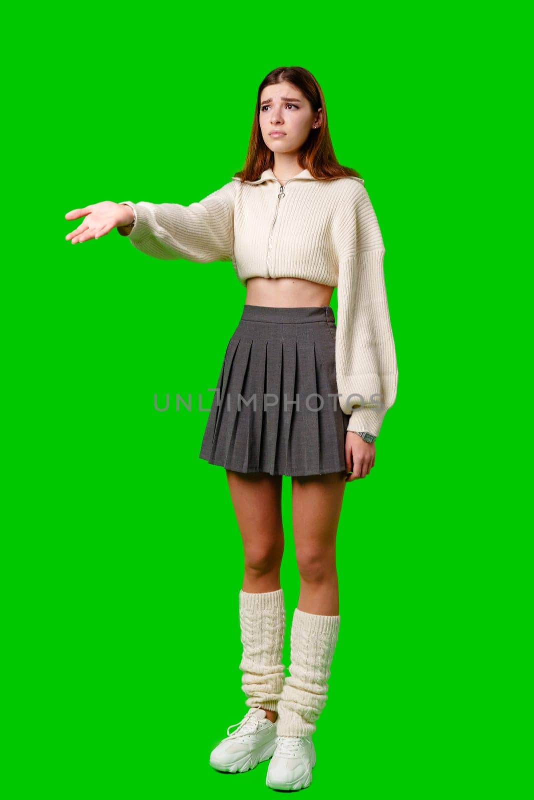 A woman dressed in a skirt and sweater is pointing at an unseen object or direction, gestures with intent and focus on something specific.
