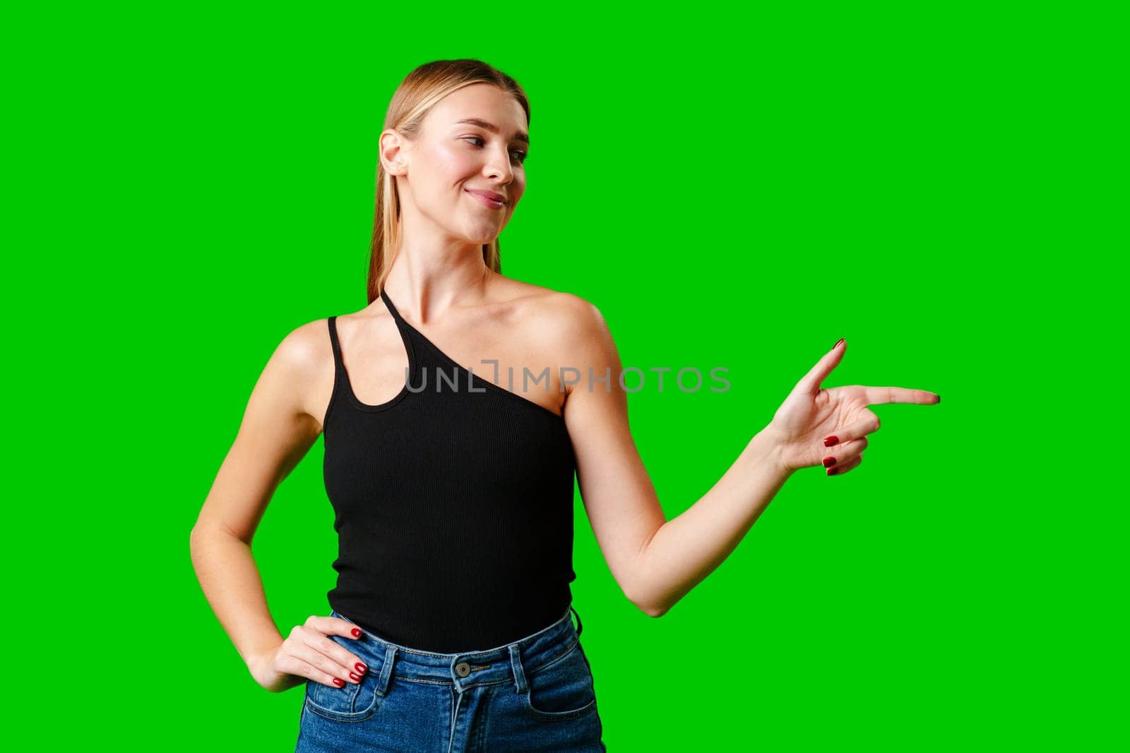 Young Woman Pointing at Something against green background by Fabrikasimf