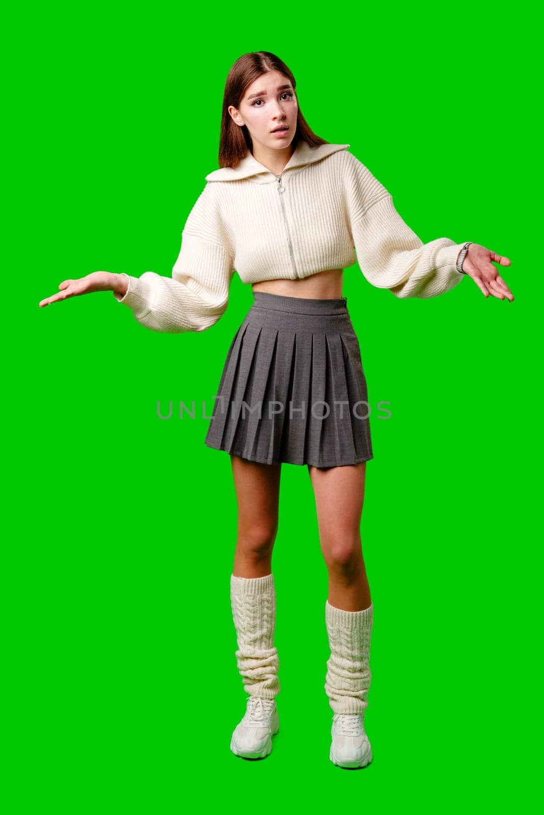 A woman is standing on a green screen backdrop, wearing a skirt and sweater. She appears poised and looking directly at the camera. by Fabrikasimf