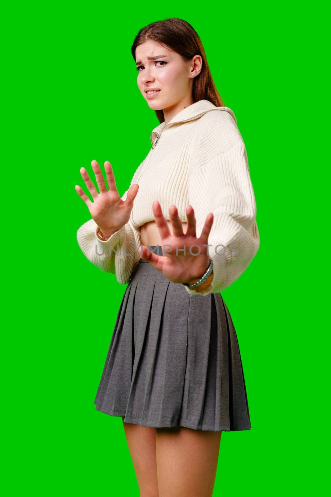 Young Woman Gesturing Stop With Both Hands Against a Green Background by Fabrikasimf