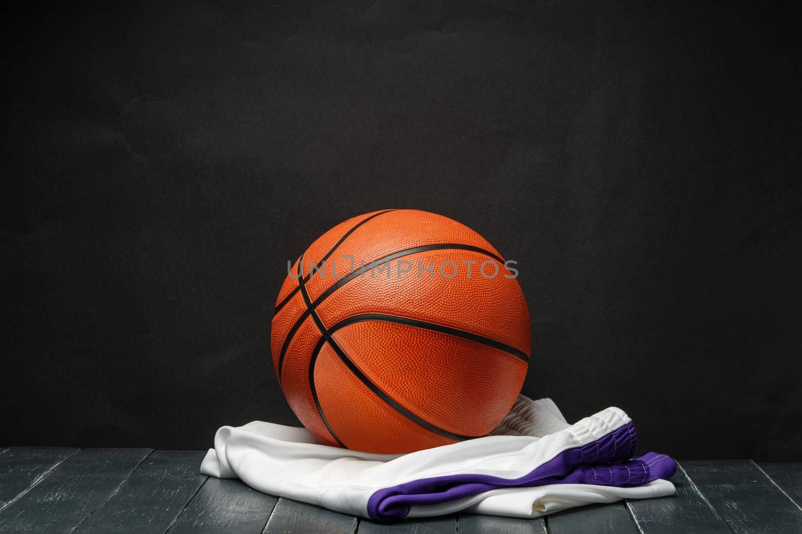 Vibrant Orange Basketball Resting on a Dark Wooden Floor With White and Purple uniform by Fabrikasimf