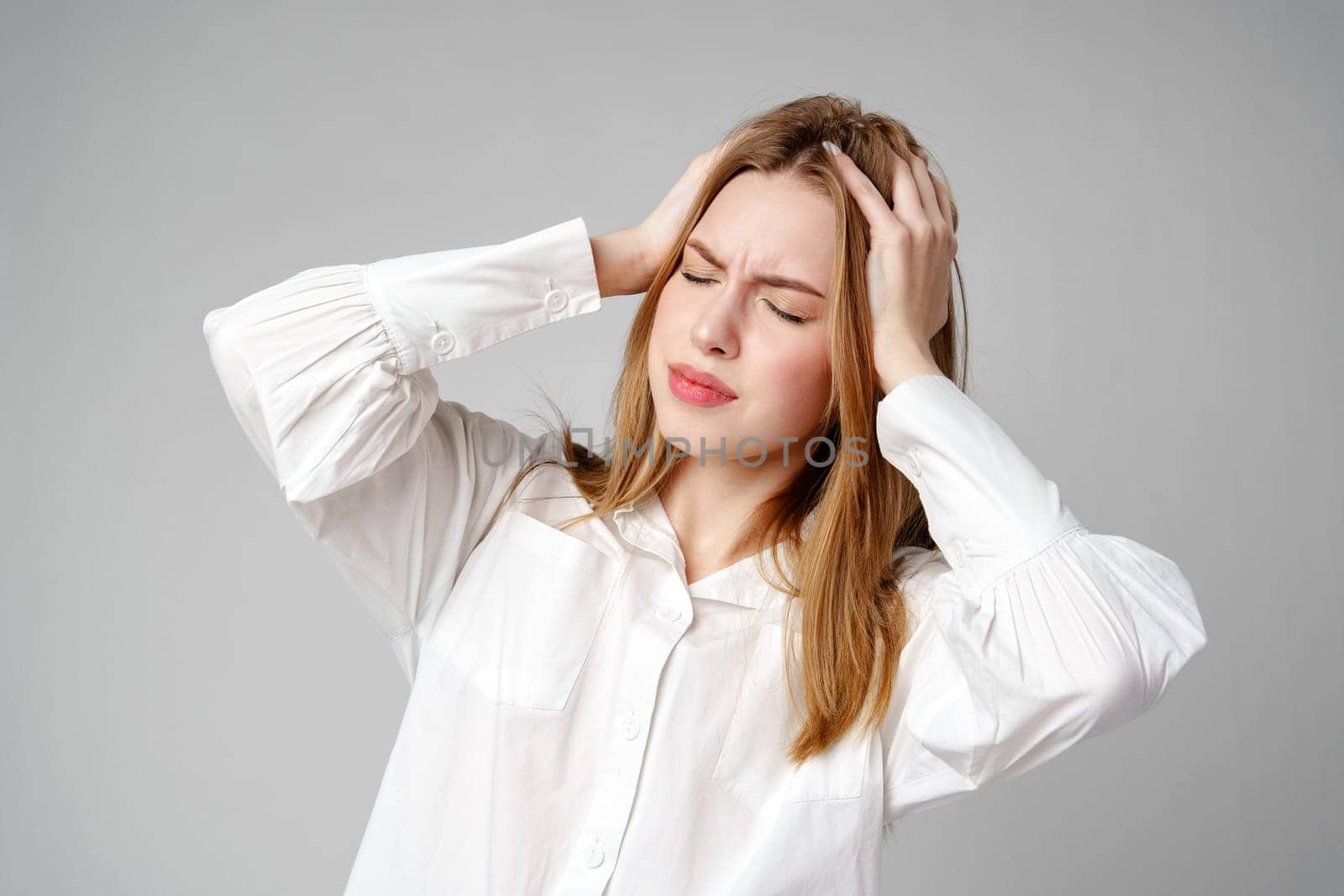 Woman With Hands on Head Suffering Headache in studio