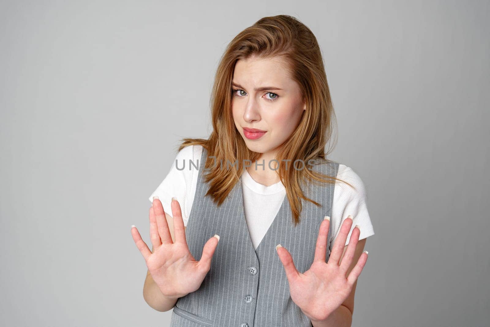 Young Woman in Vest Holding Hands Up in Studio