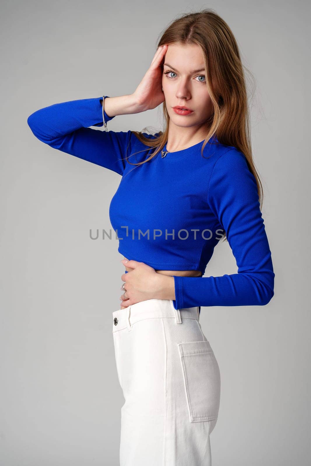 Young Woman model in Blue Top and White Pants posing on white background in studio