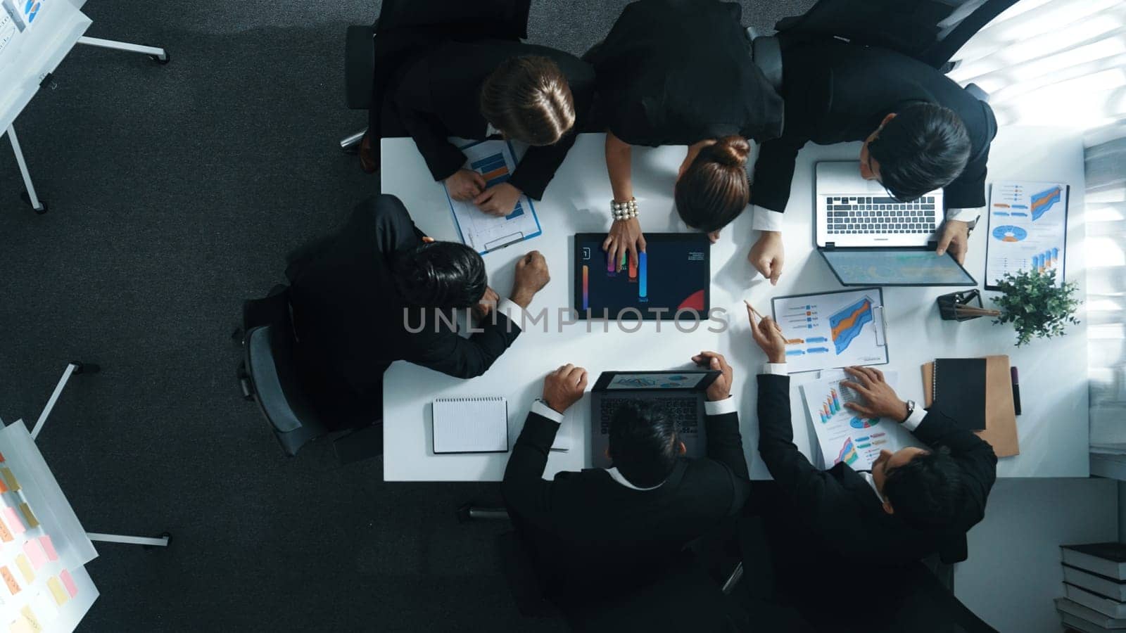 Top view of smart business people brainstorm marketing idea at meeting table while compare stock market investment data between laptop and tablet. Business team planning financial plan. Directorate.