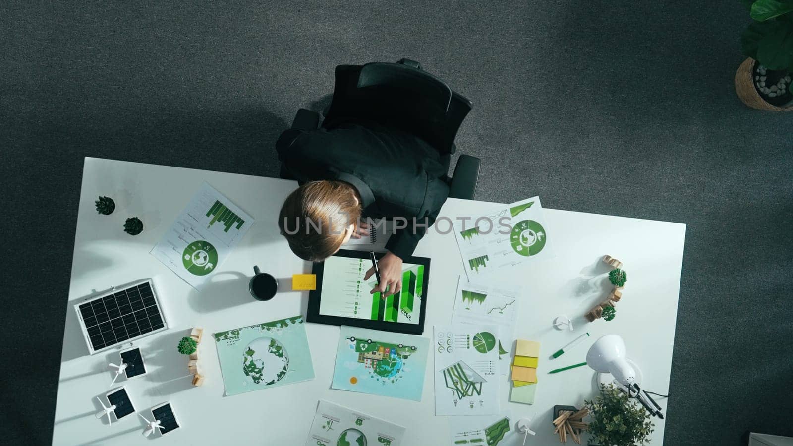 Top view of smart manager making decision about green business investment. Aerial view of skilled business woman working at meeting table with document about green energy and zero waste. Alimentation.