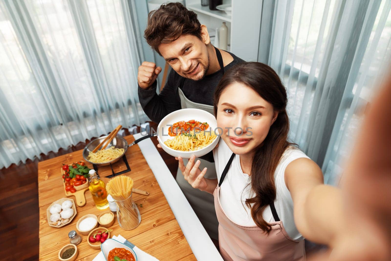 Making photo selfie in couple chef influencers completely cooked spaghetti with meat topped with tomato sauce special dish recording on camera, serving healthy food at modern home chanel. Postulate.