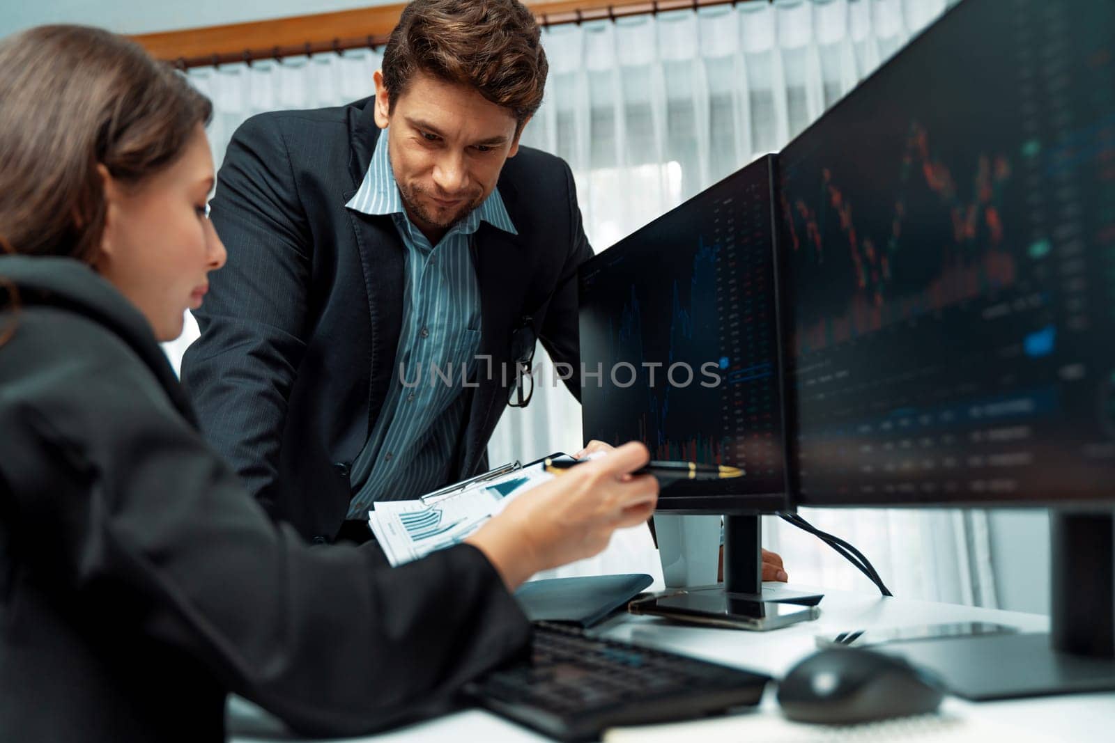 Two business traders discussing value business statistic graph company on paper report analyzing with dynamic stock exchange market currency real time website surround pc screens at office. Postulate.