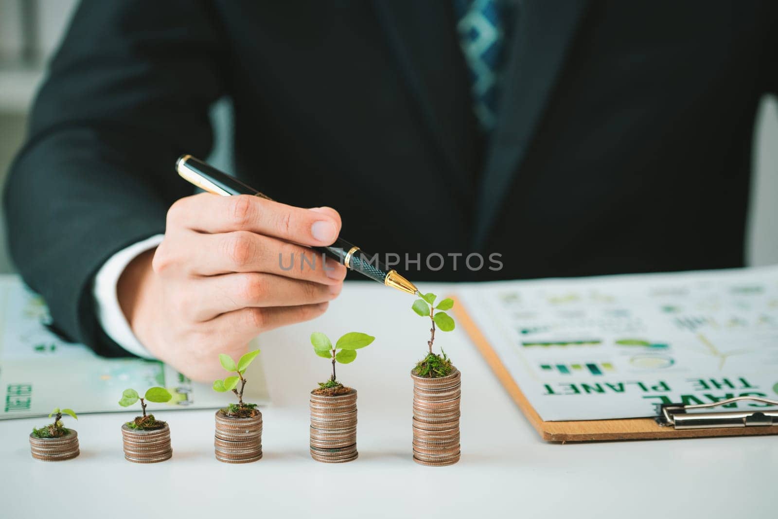 Businessman with coin stack at his office as sustainable money growth. Gyre by biancoblue