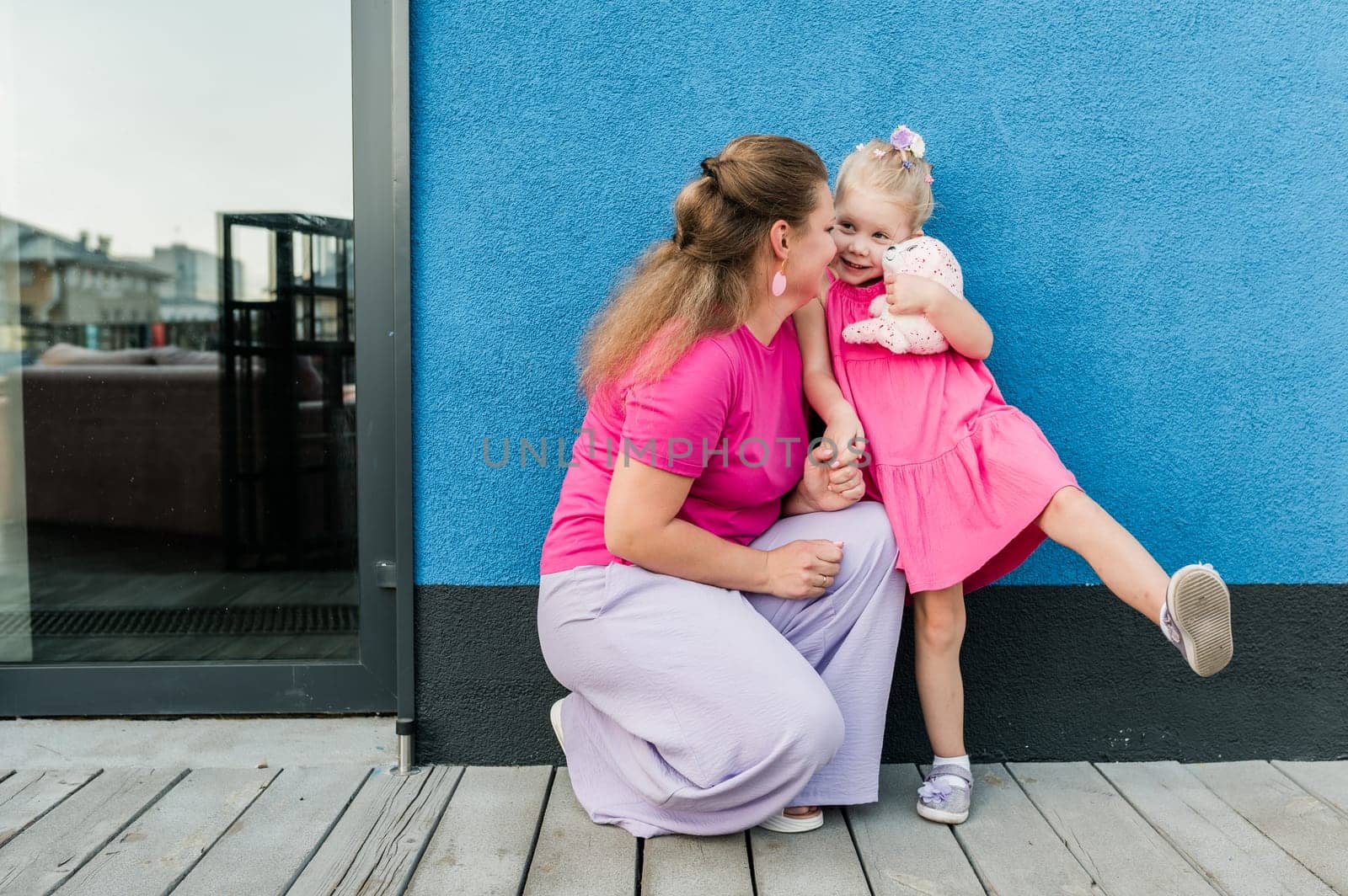 Blonde little girl with cochlear implant playing with her mother outdoor. Hear impairment deaf and health concept. Diversity and inclusion. Copy space.