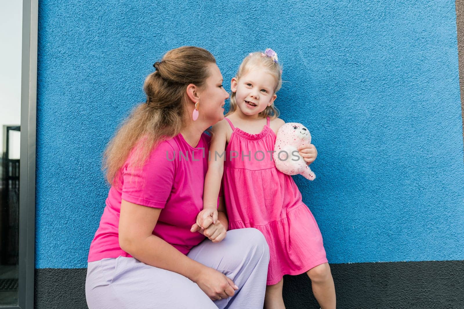 Blonde little girl with cochlear implant playing with her mother outdoor. Hear impairment deaf and health concept. Diversity and inclusion. Copy space.