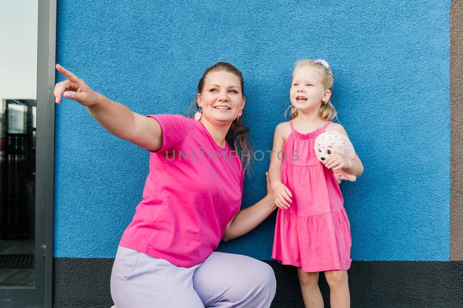 Blonde little girl with cochlear implant playing with her mother outdoor. Hear impairment deaf and health concept. Diversity and inclusion. Copy space.