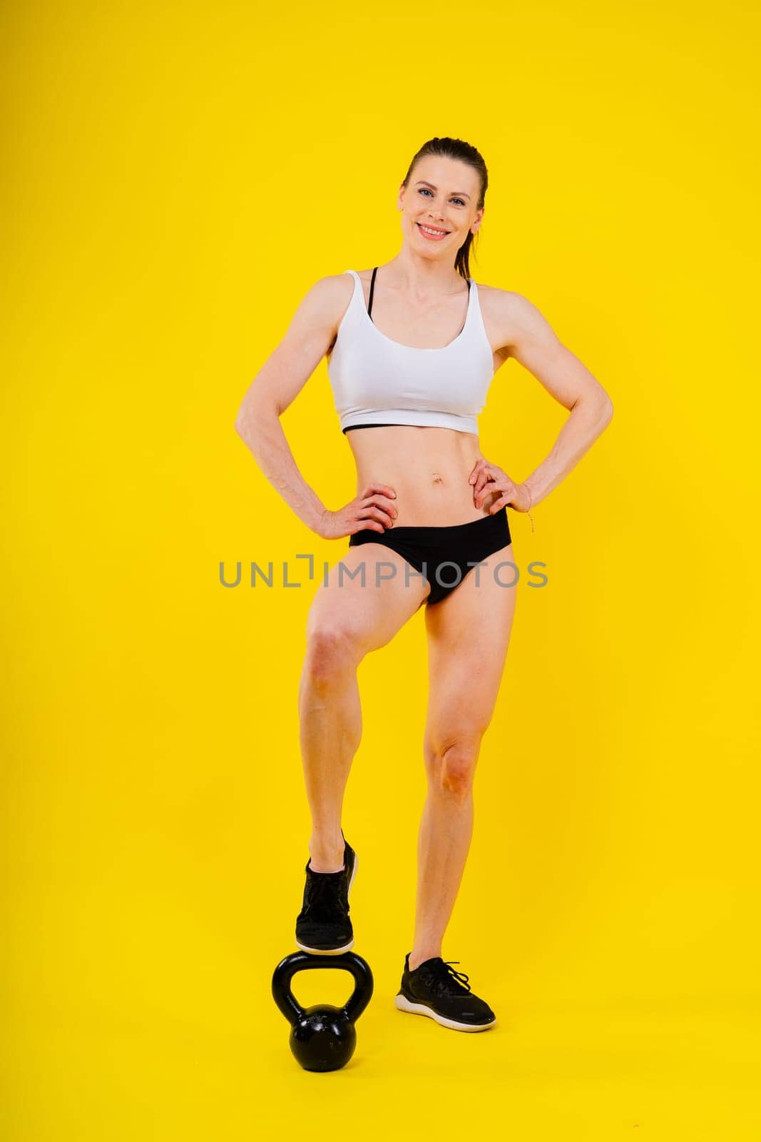 Sport, active lifestyle concept. Smiling strong and slim fitness female athlete holding kettlebells