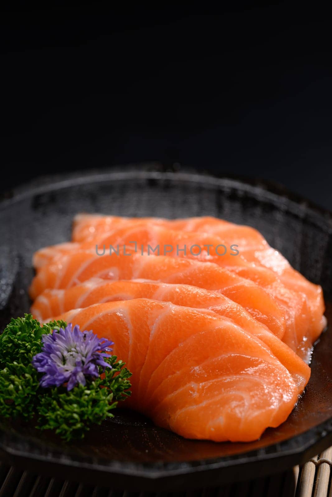 Closeup salmon sashimi on black plate. Japanese food style concept by prathanchorruangsak