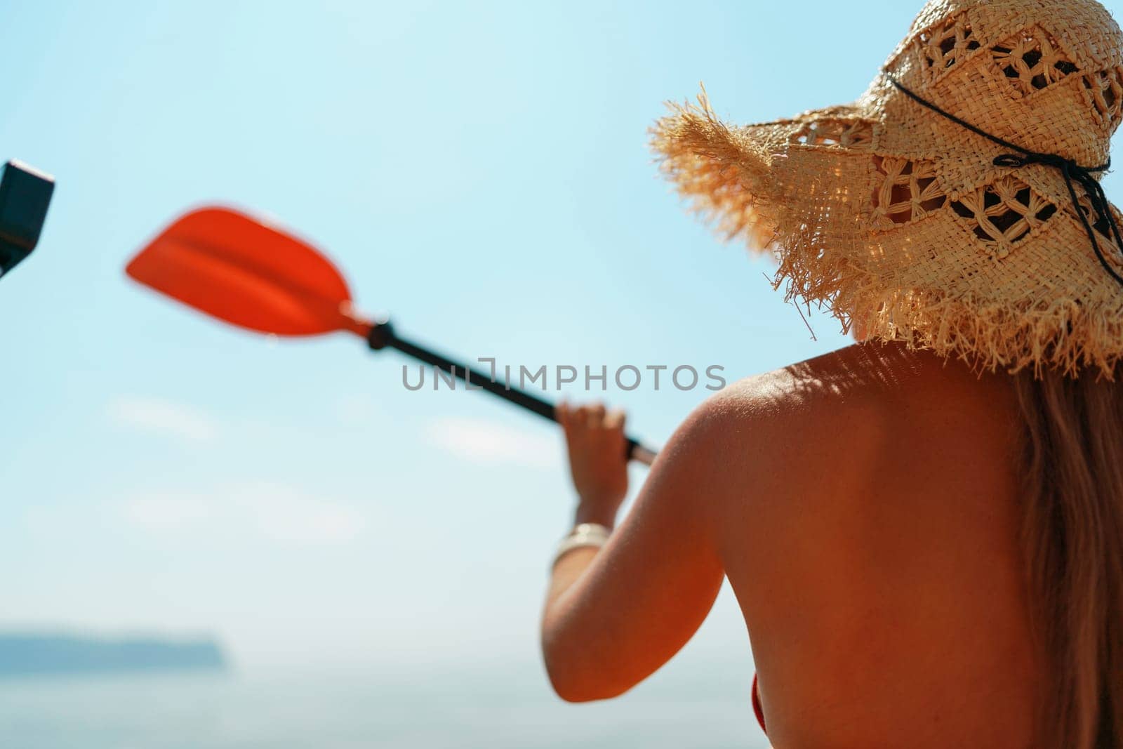 Woman in kayak back view. Happy woman with long hair in a swimsuit and hat floating in kayak on the sea. Summer holiday vacation. Summer holidays vacation at sea. by Matiunina
