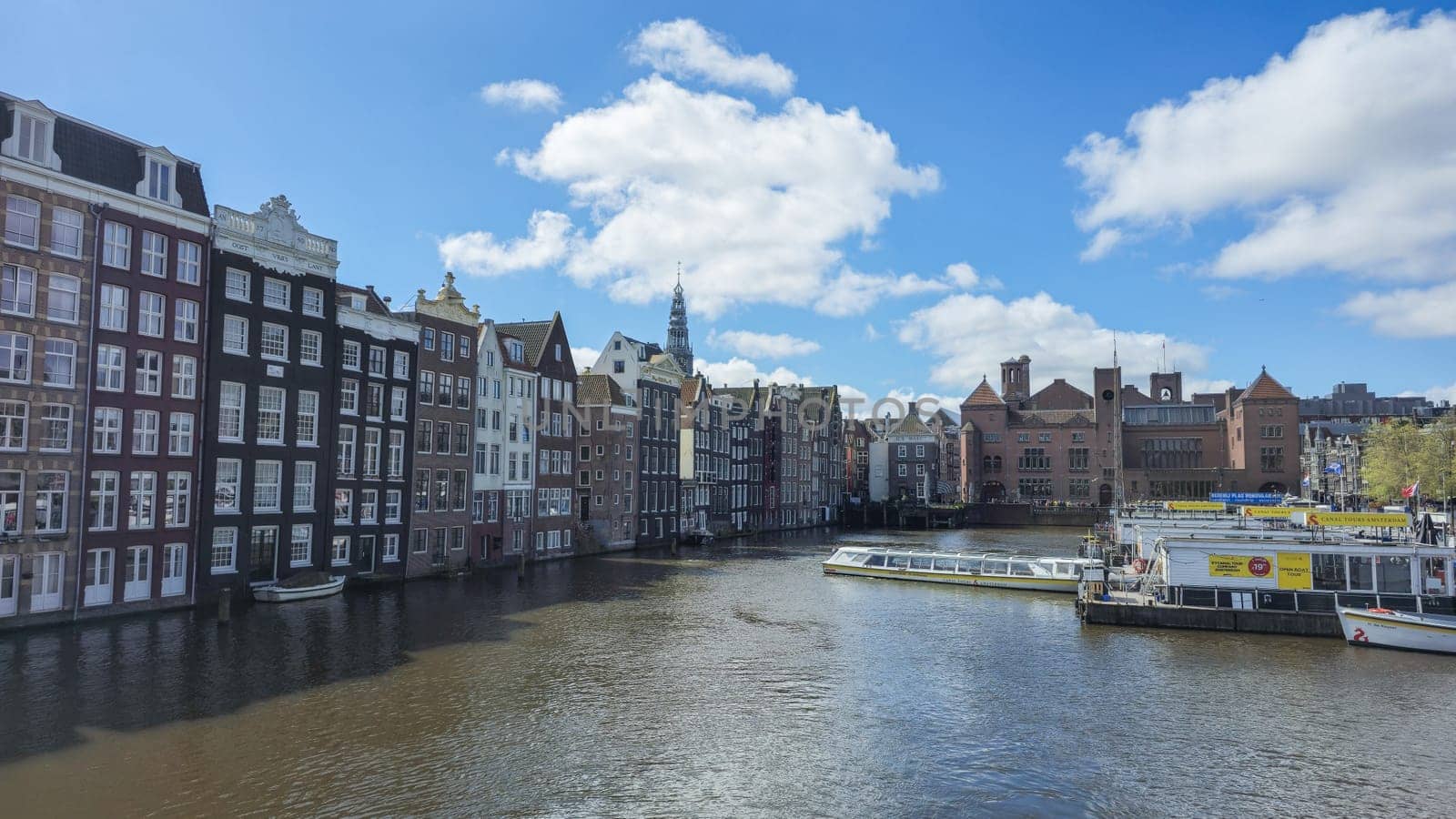 Amsterdam Netherlands 21 April 2024, Boats leisurely float on the river next to modern skyscrapers, creating a serene juxtaposition of nature and urban life.