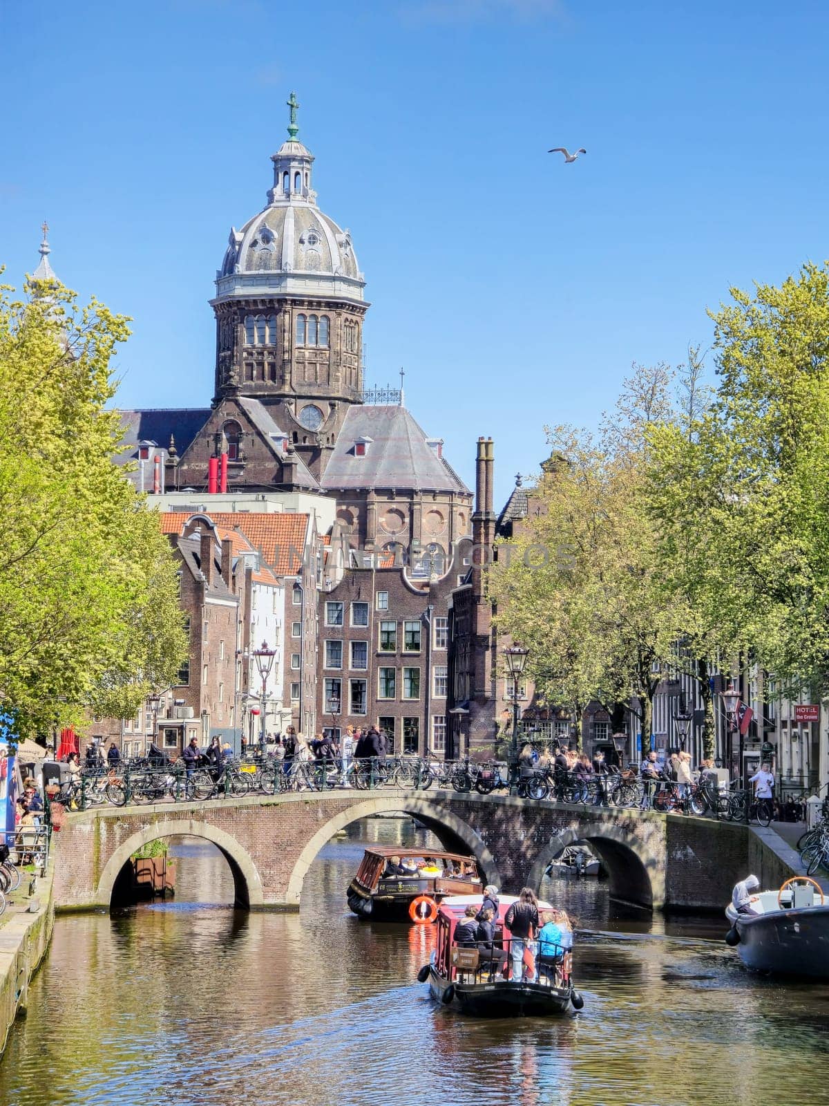 Amsterdam Netherlands 21 April 2024, A boat peacefully glides down the river, surrounded by towering buildings that create a stark urban landscape.