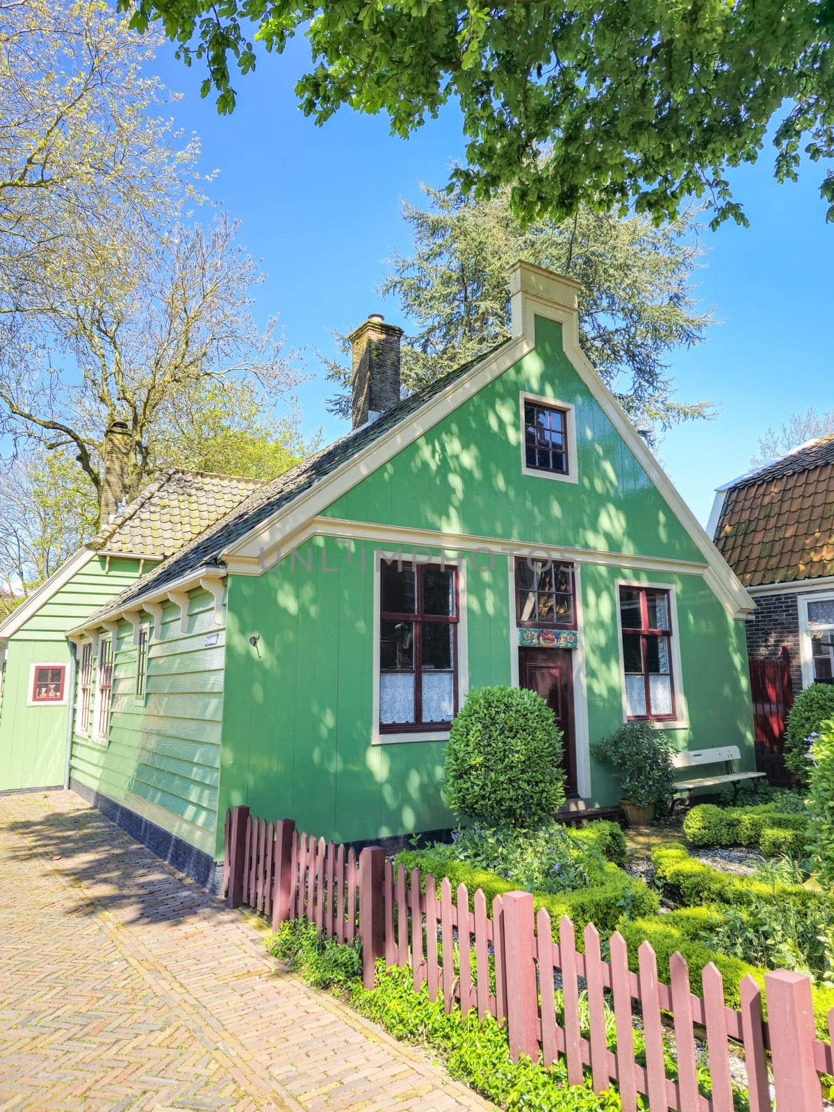 A charming green house stands surrounded by a picket fence, exuding a sense of tranquility and serenity in its quaint setting. Broek in Waterland Netherlands 21 April 2024