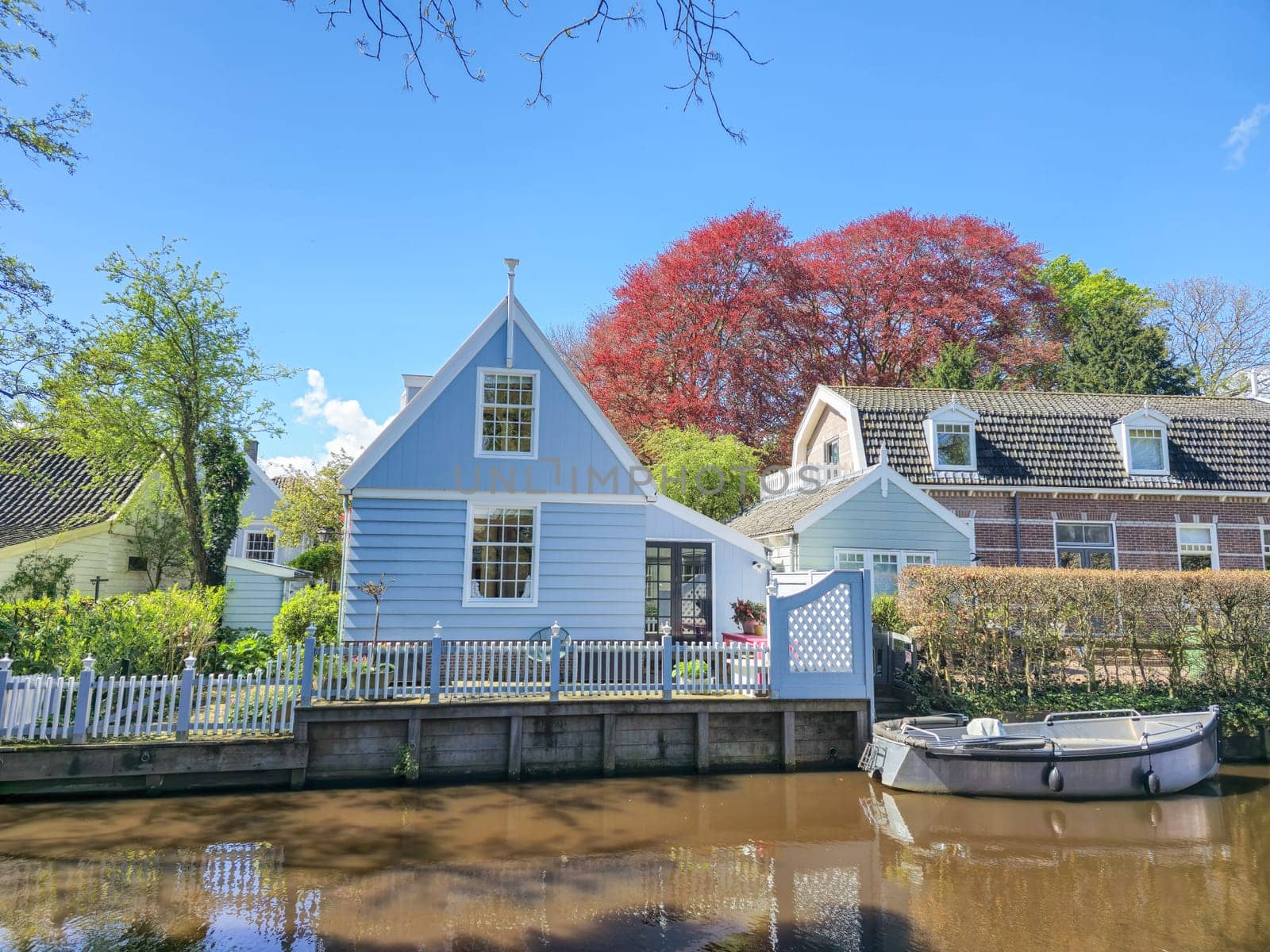 A quaint blue house peacefully sits beside a calm body of water, surrounded by a tranquil and picturesque setting. Broek in Waterland Netherlands