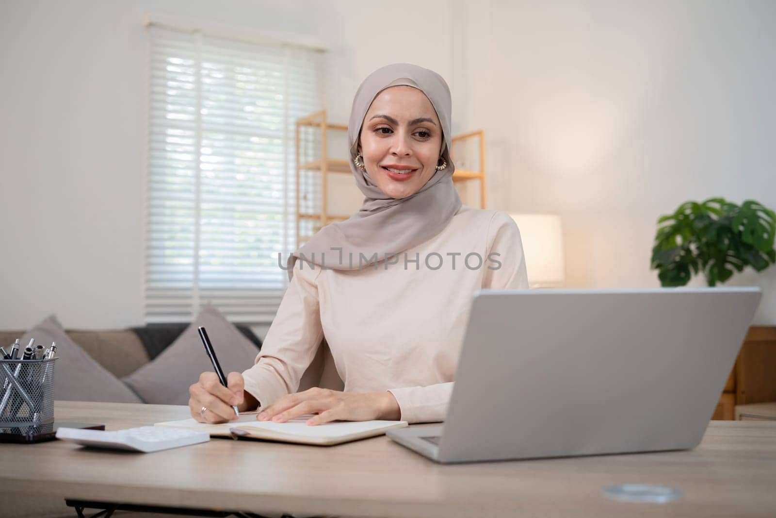 Muslim businesswoman working using laptop and taking notes on documents In the modern office.