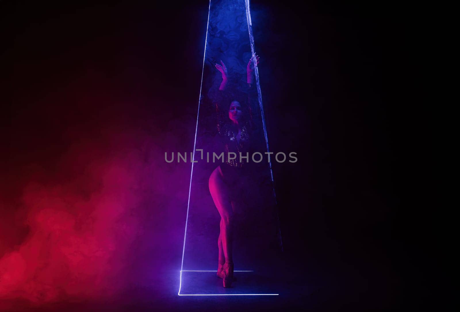 Ballet dancer in pointe under multicolor neon laser light on stage. Woman ballerina posing in dark room. Performance, projection mapping. Interactive installation, Optical visuals. Quality photo