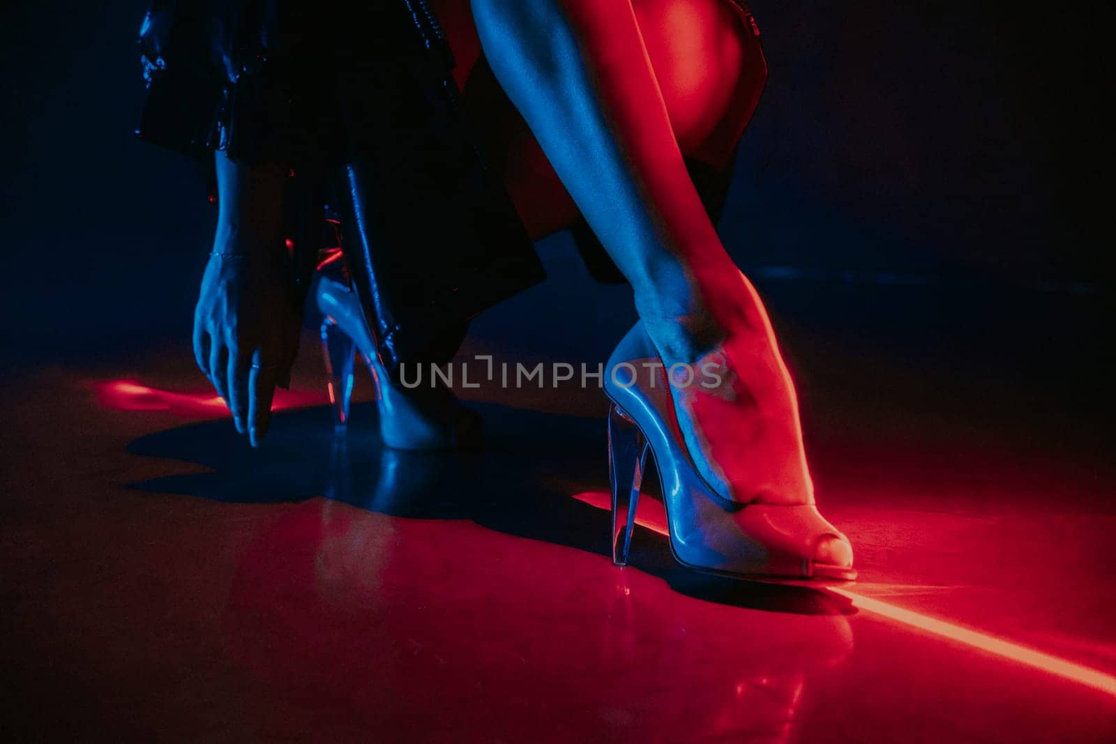 Legs of gorgeous woman in high heels shoes under red illumination, laser light, neon club. Projection illusion mapping. High quality photo