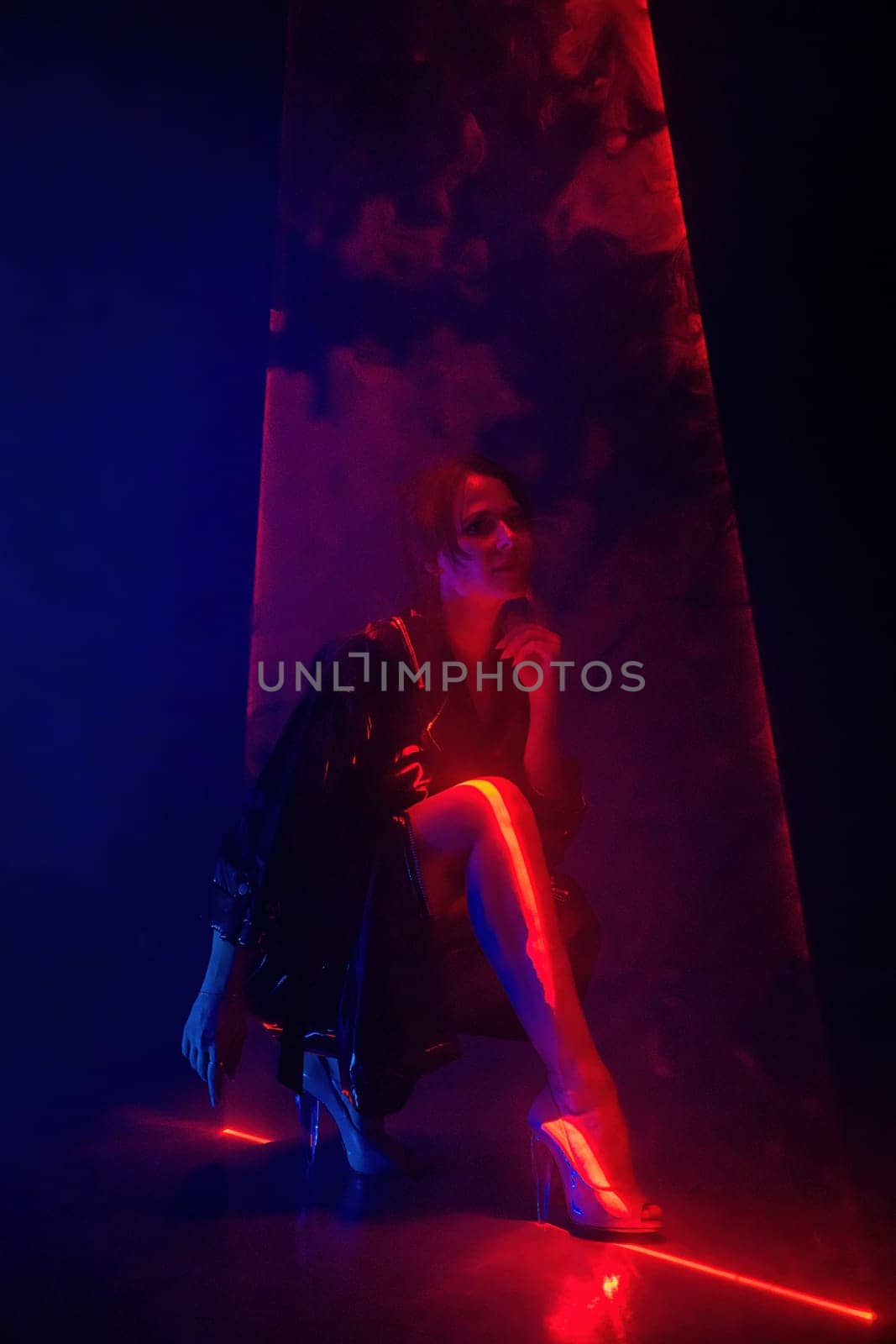 Gorgeous woman in latex coat under colorful illumination, laser light, neon smoke club. Projection illusion mapping. Futuristic model. High quality