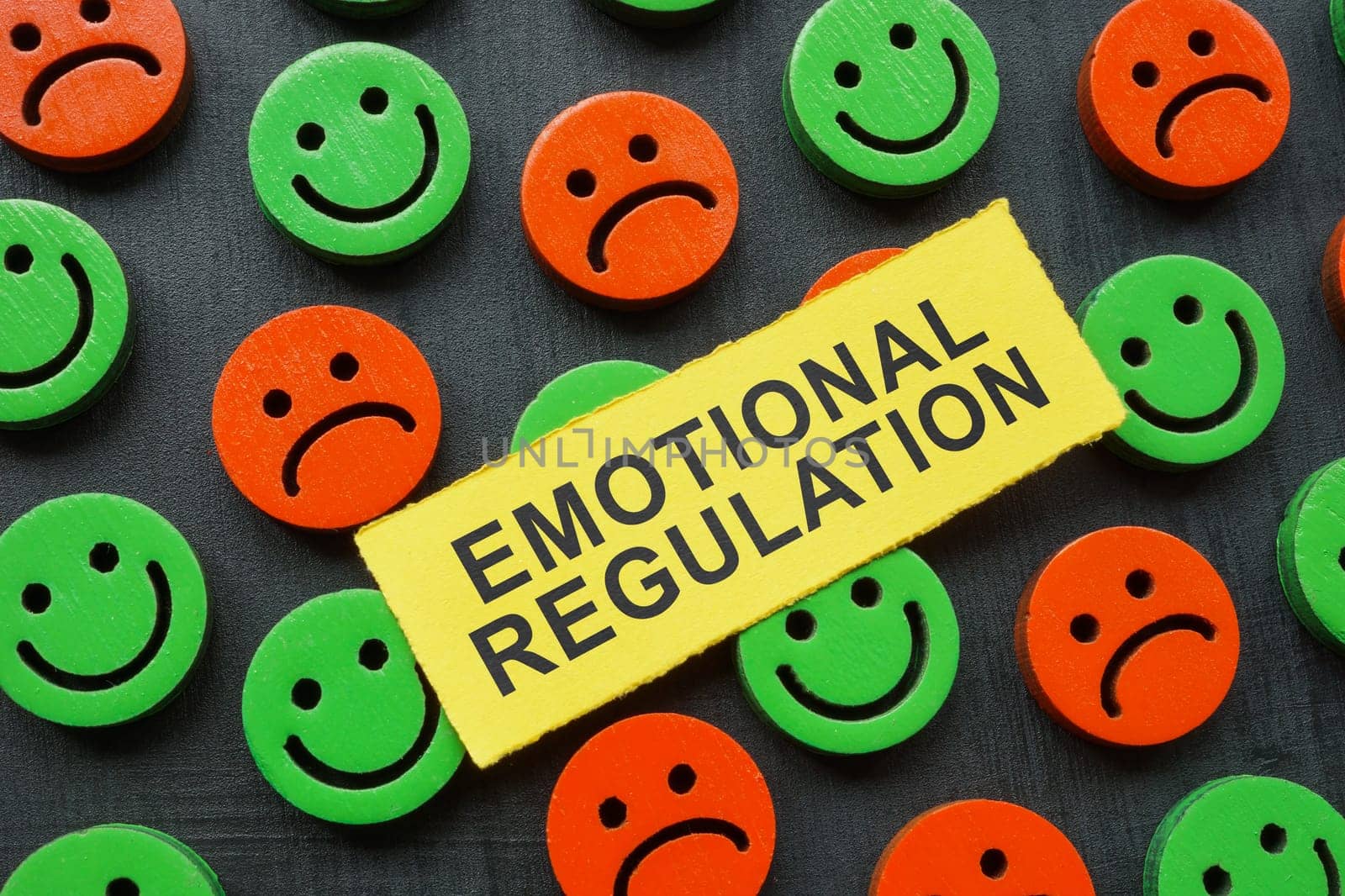 The inscription emotional regulation lies on happy and sad emoticons. by designer491