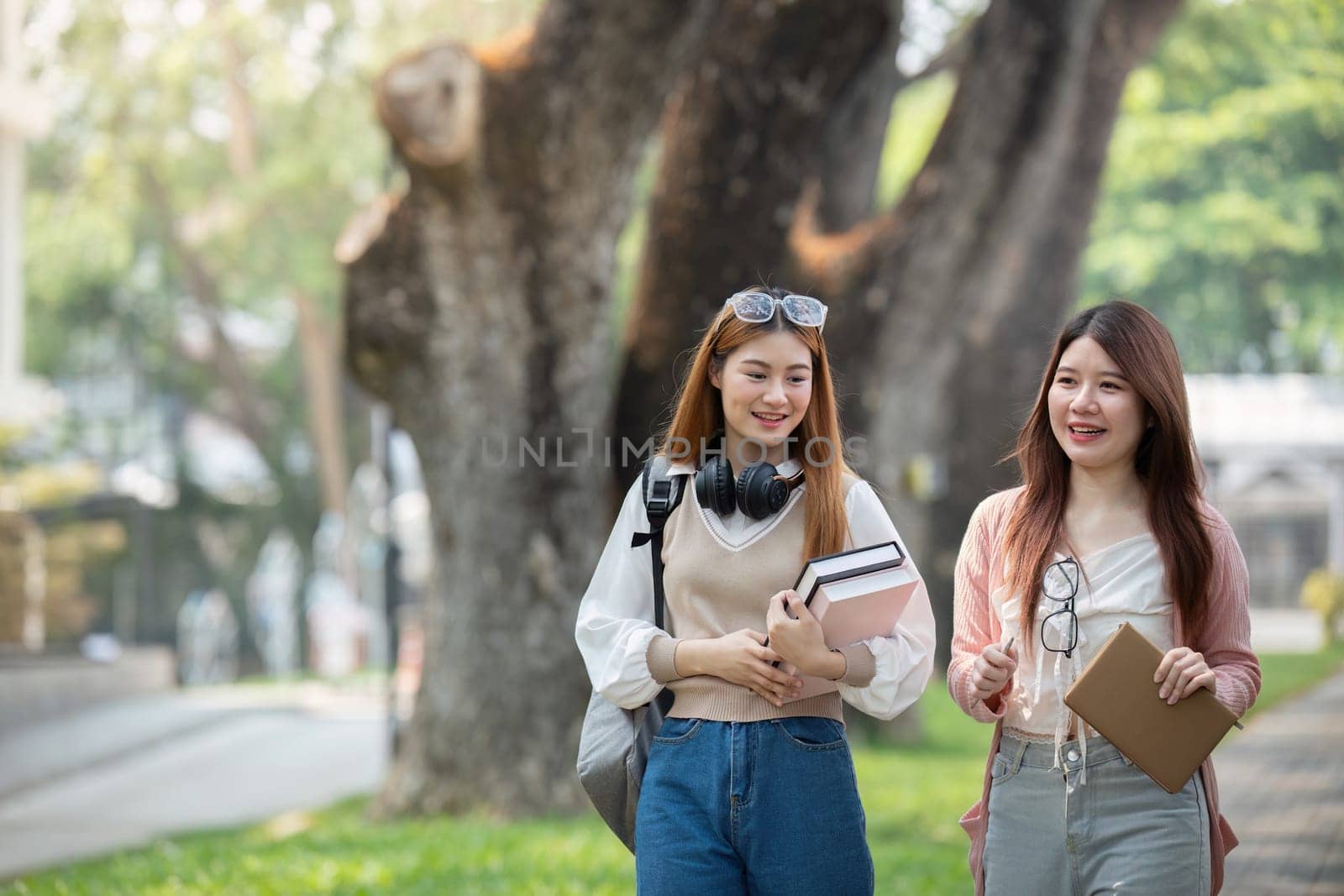 University student girl friends with learning book college while walking in campus.