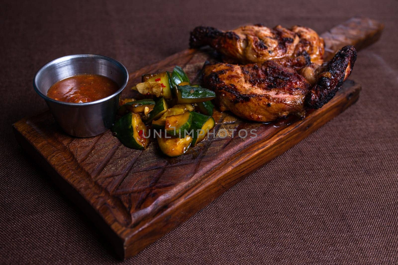 Juicy grilled chicken with crispy skin, fresh cucumber, and spicy sauce. A delectable meal for any occasion.