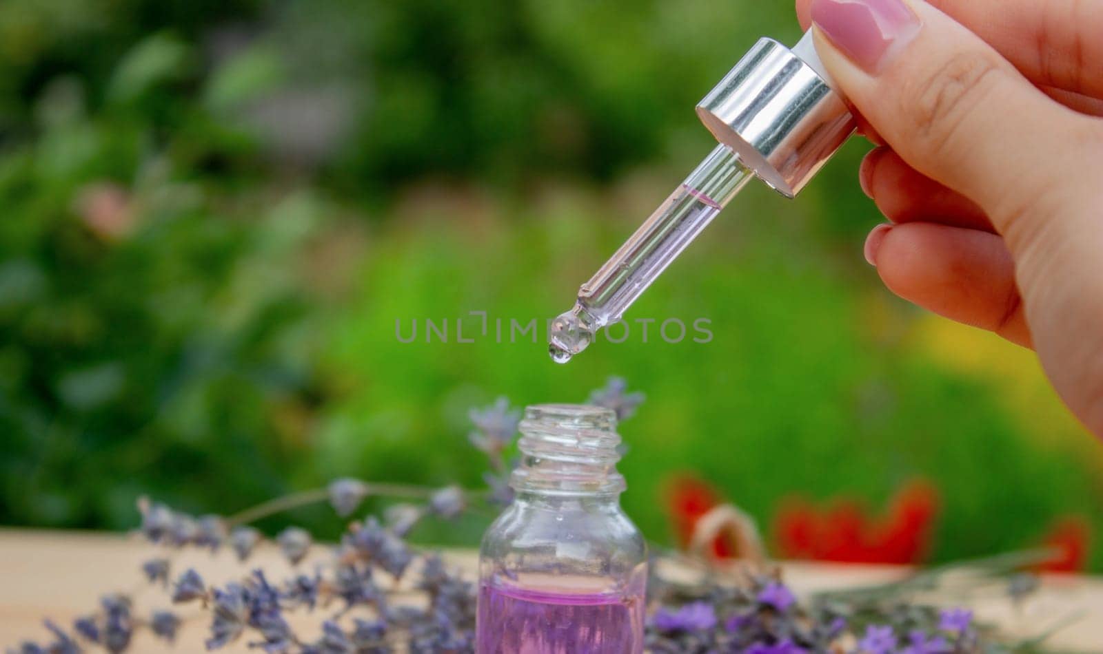 Glass bottle of lavender essential oil on a wooden background. by Anuta23