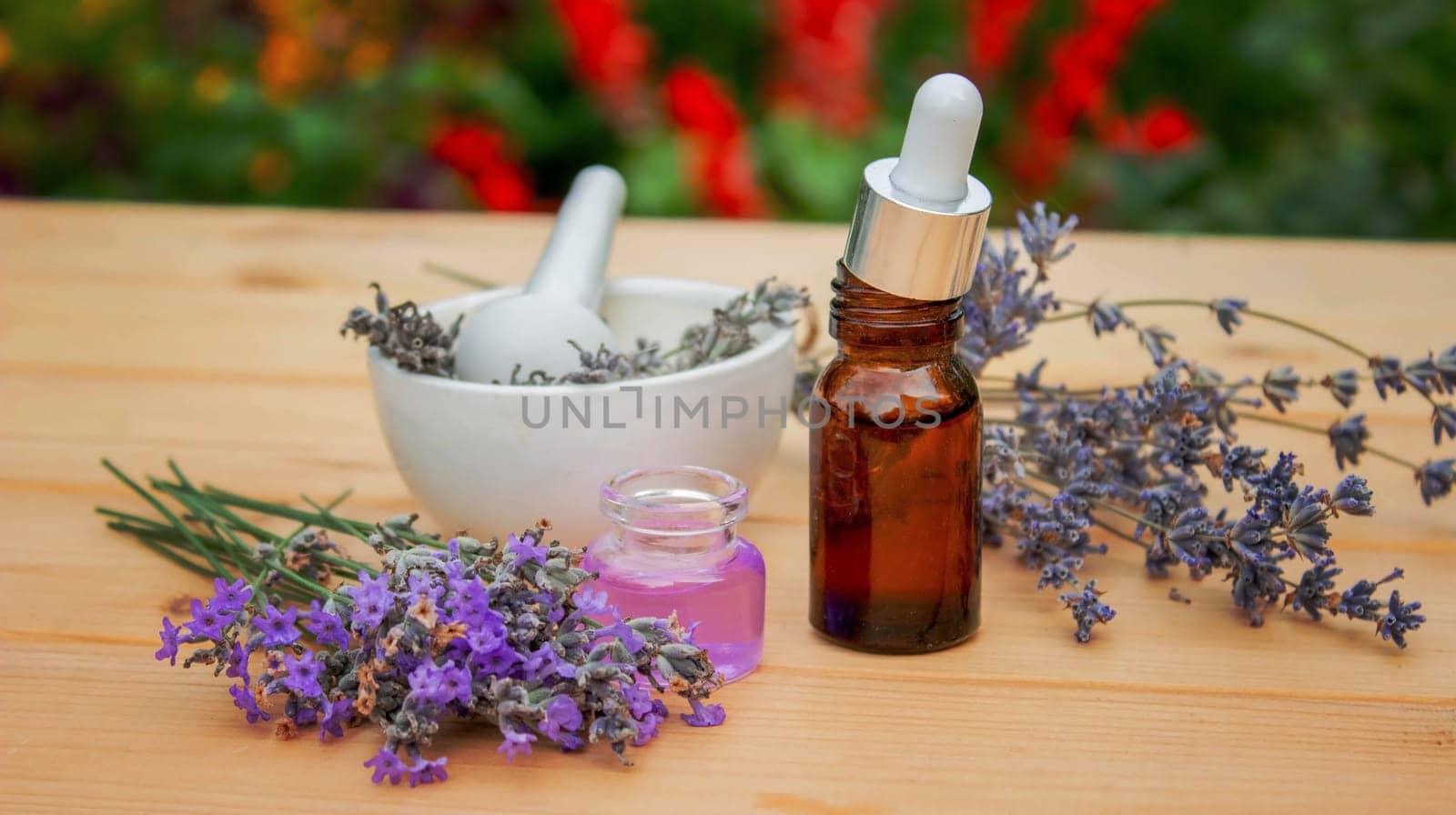 Glass bottle of lavender essential oil on a wooden background