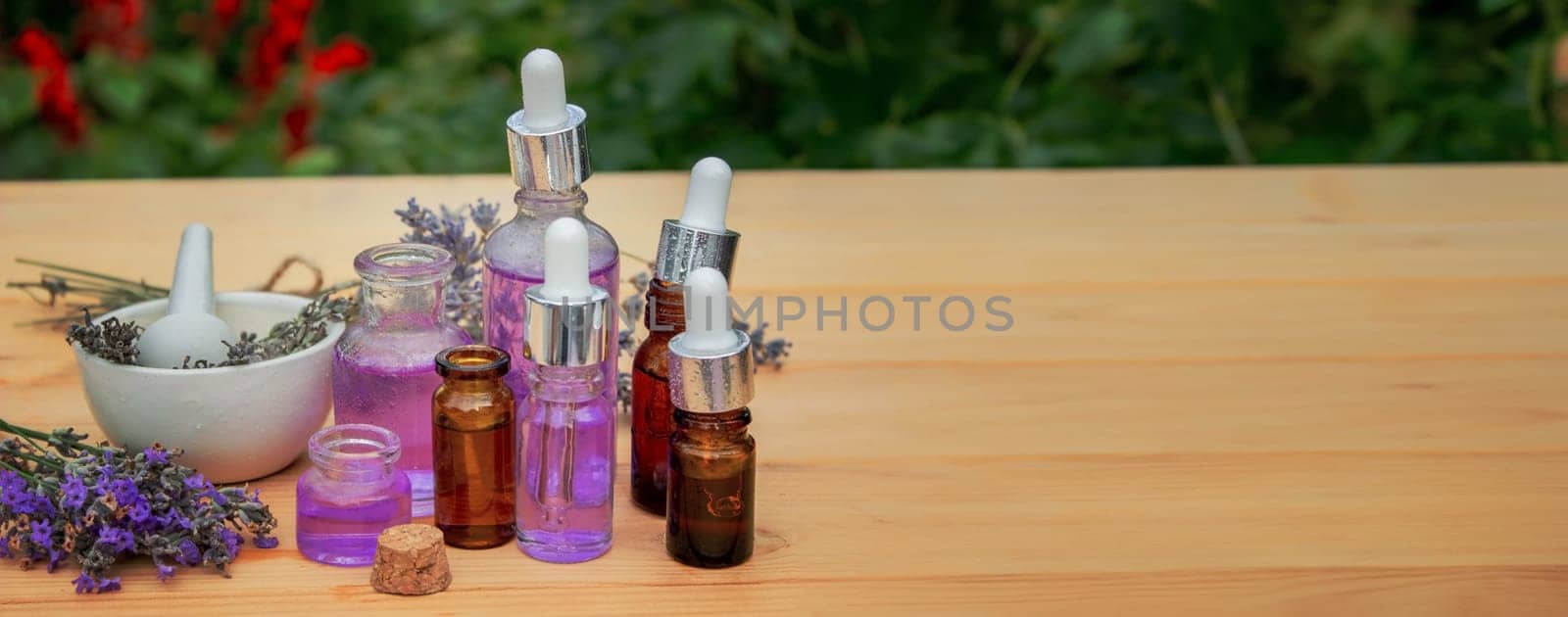Glass bottle of lavender essential oil on a wooden background