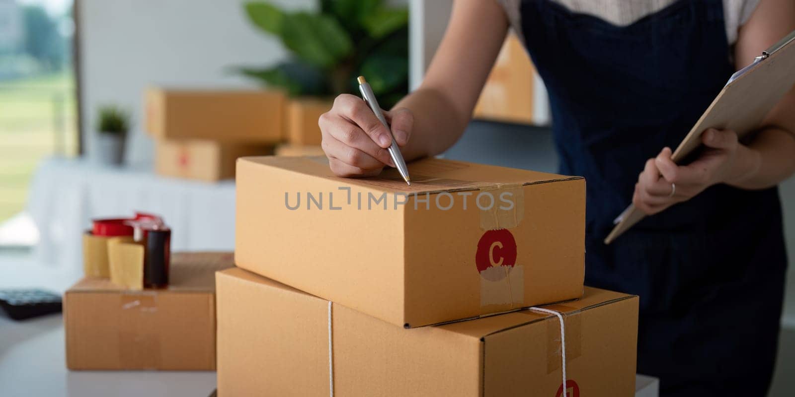 Woman in an online store check the customer address and package information on box. Online shopping concept.